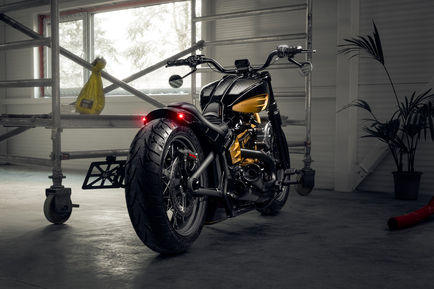 Harley Davidson motorcycle with Killer Custom "Rodstr" rear fender from the rear in a modern garage  with equipment in the background
