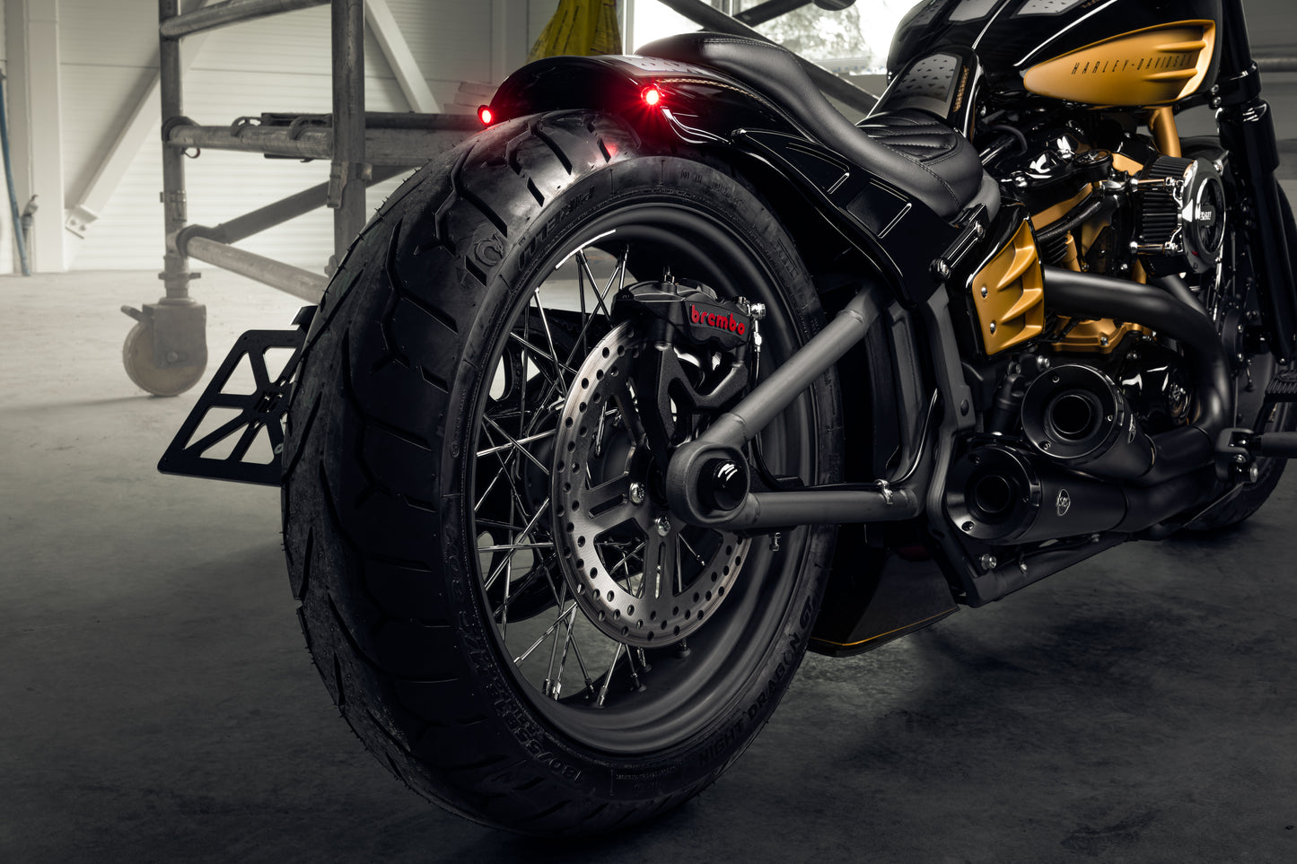 Zoomed Harley Davidson motorcycle with Killer Custom "Rodstr" rear fender from the rear in a modern garage