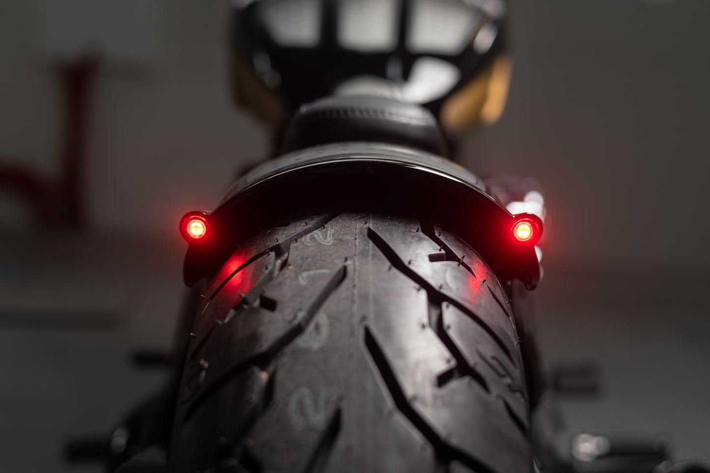 Zoomed Harley Davidson motorcycle with Killer Custom "Rodstr" rear fender from the rear blurry background