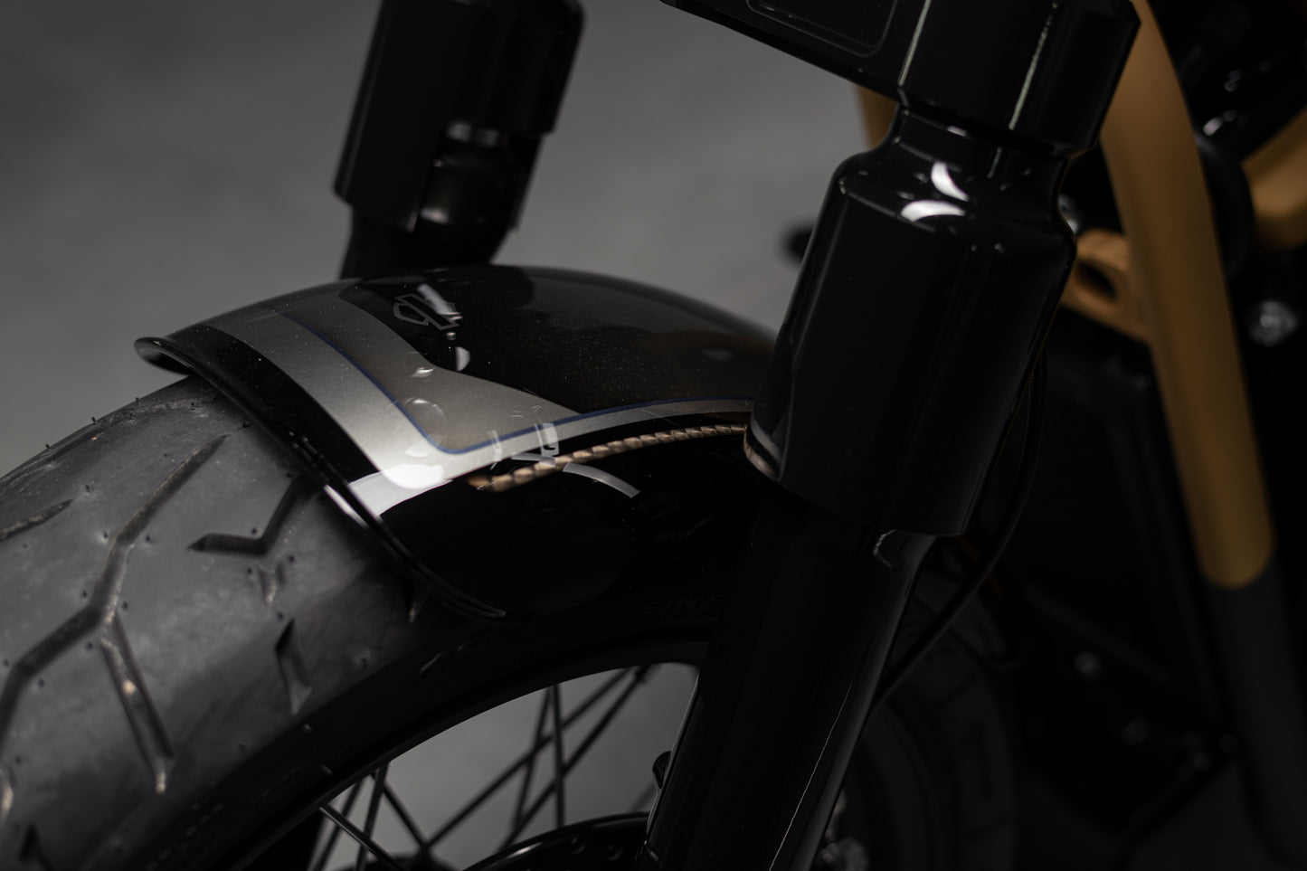 Zoomed Harley Davidson motorcycle with Killer Custom front wide wheel fender grey background