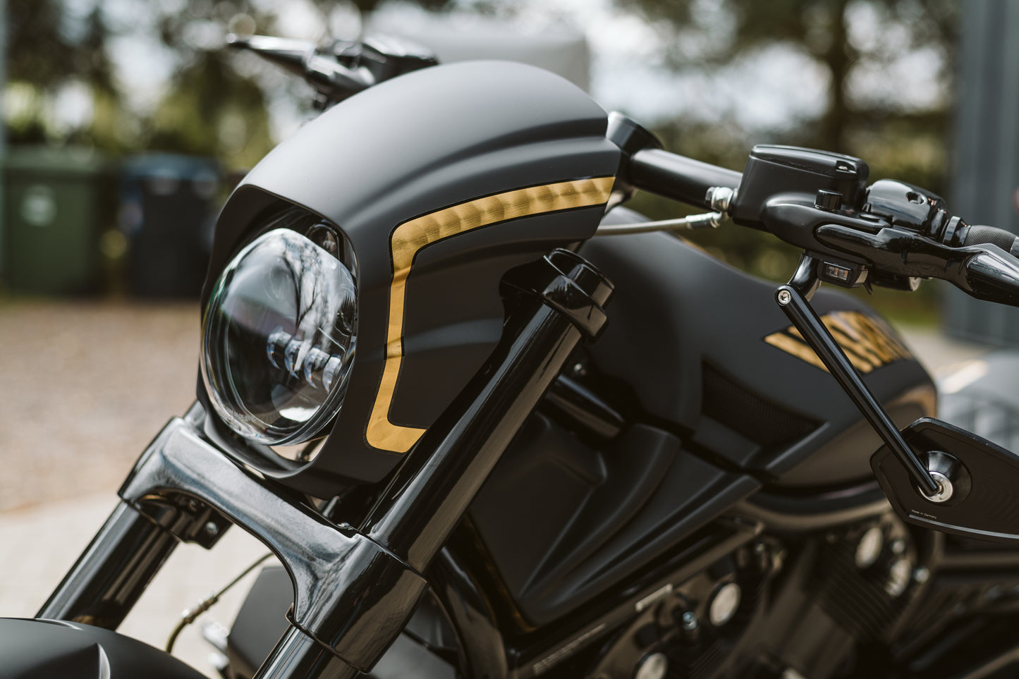 Zoomed Harley Davidson motorcycle with Killer Custom "Aggressor" V-Rod headlight fairing blurry nature background