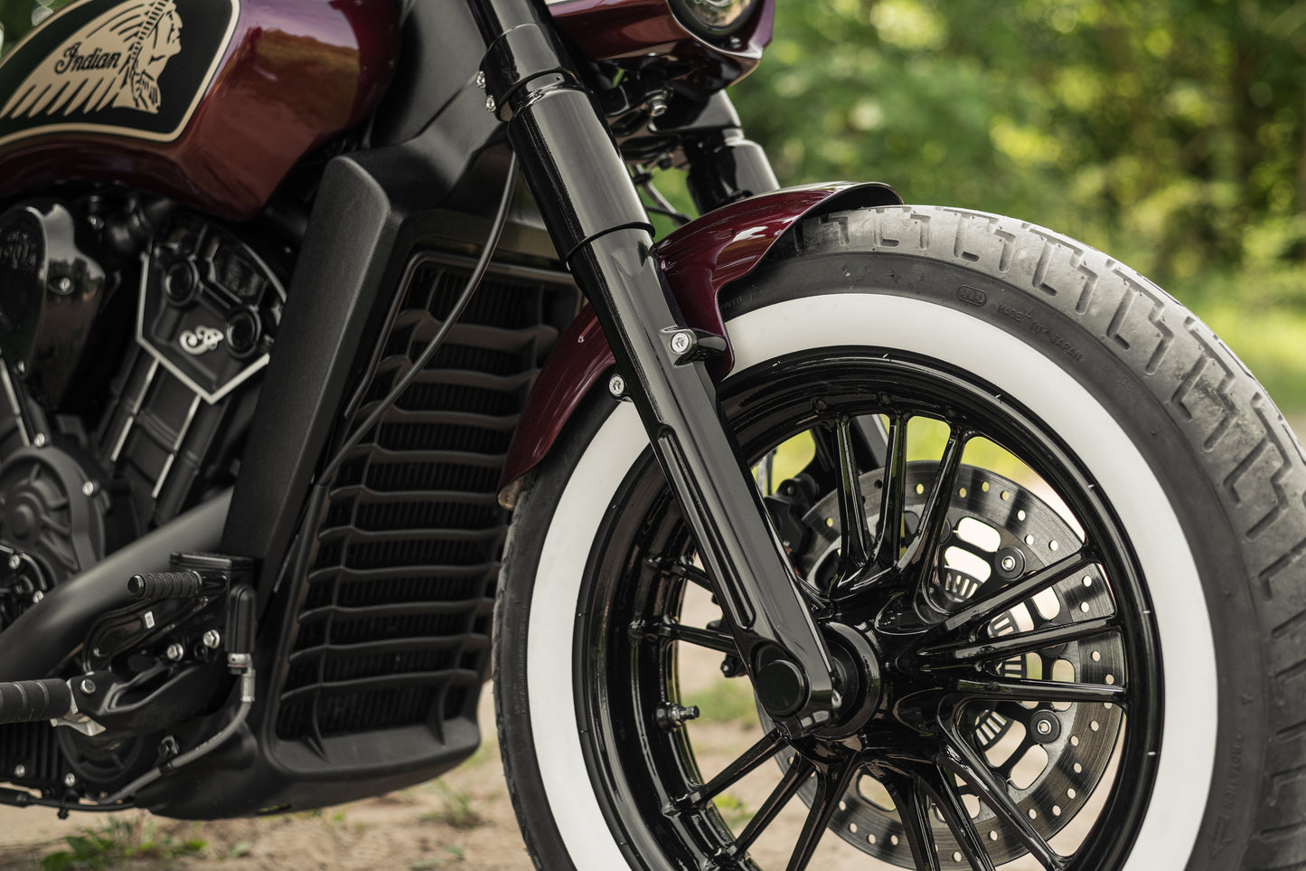 Zoomed Harley Davidson motorcycle with Killer Custom "Tomahawk" series front fender from the side in the forest on a sunny day