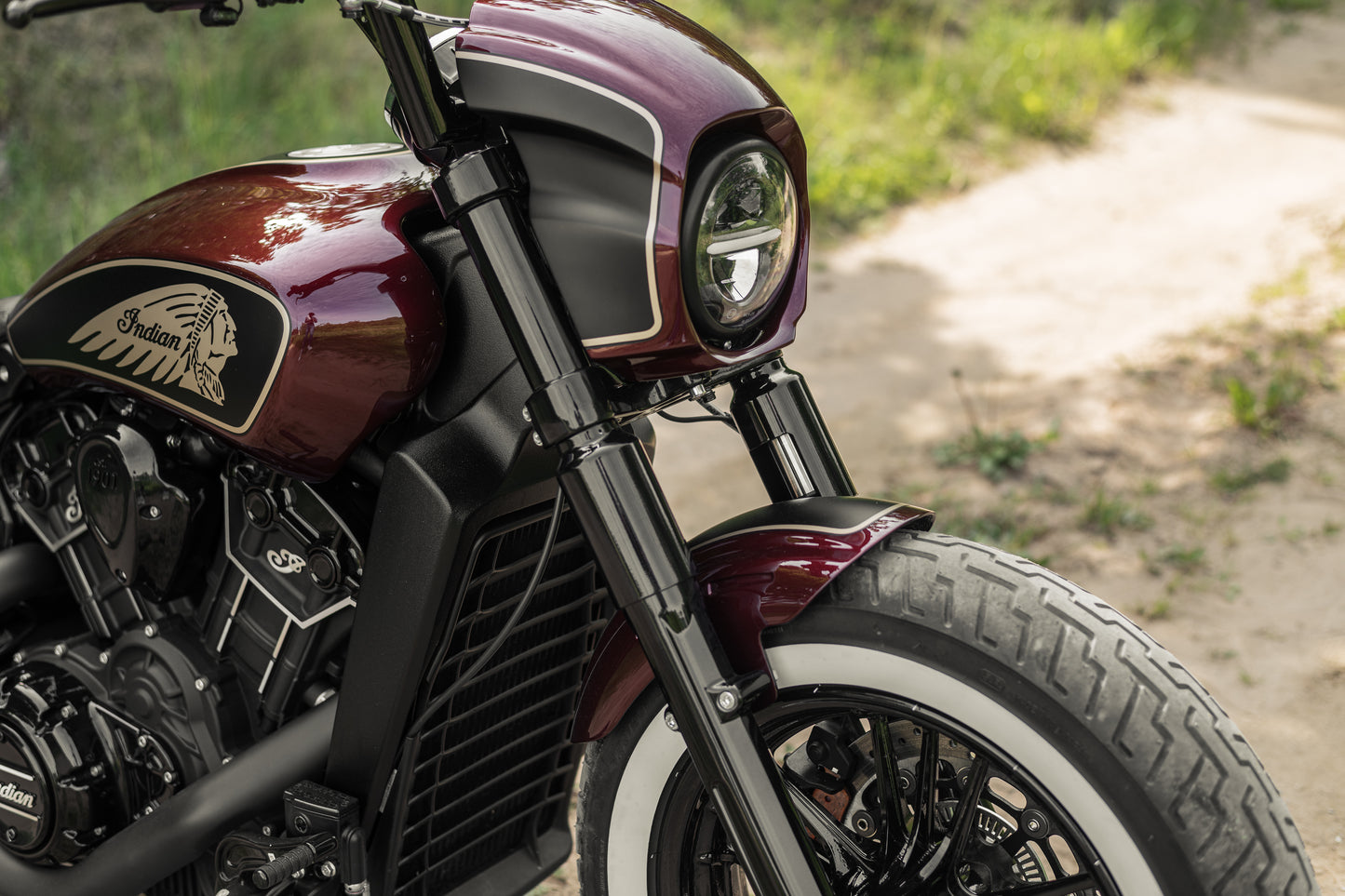 Zoomed Harley Davidson motorcycle with Killer Custom "Tomahawk" full fork covers set from the side on a roadside with blurred grass in the background