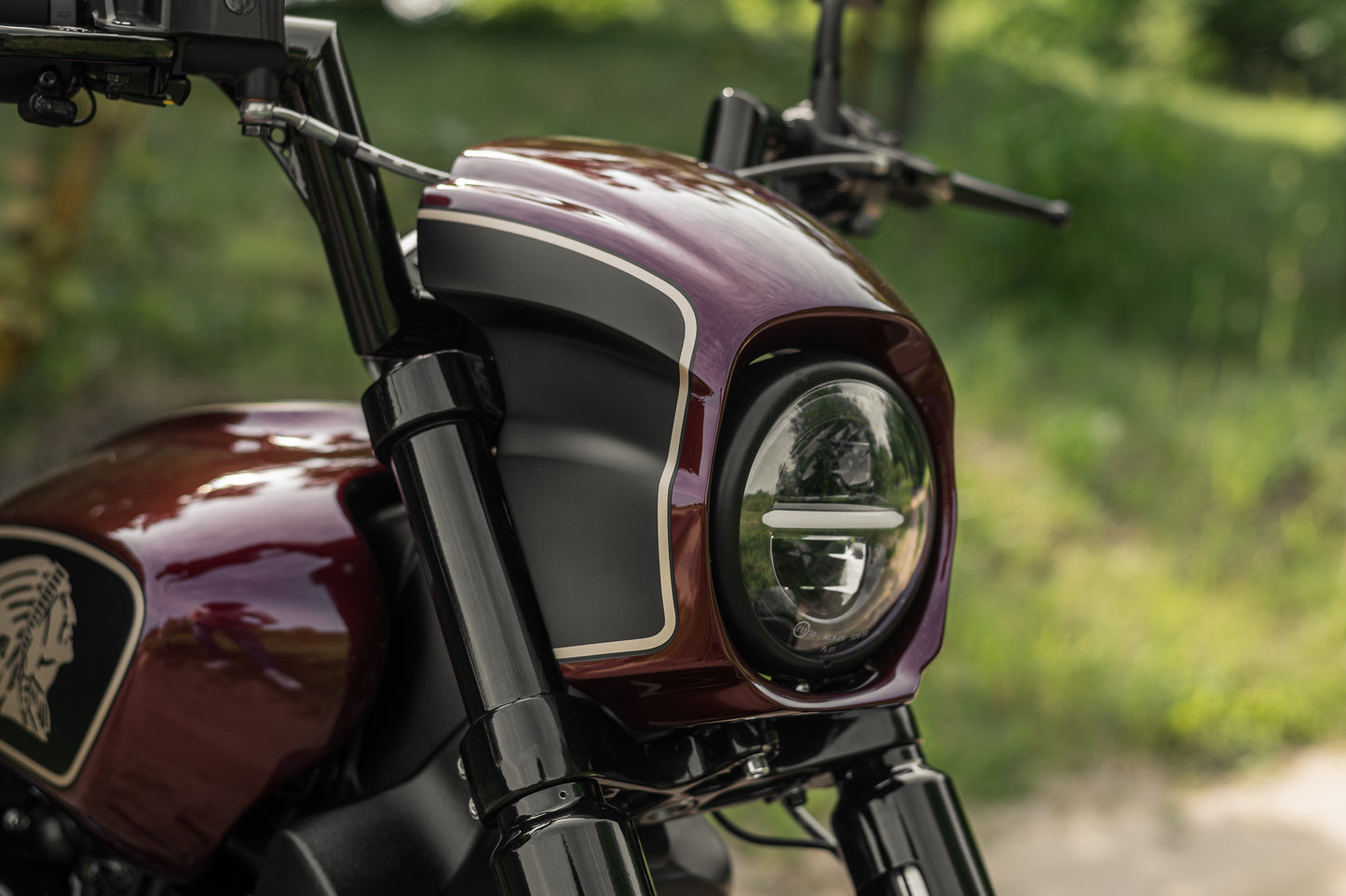 Zoomed Harley Davidson motorcycle with Killer Custom "Tomahawk" series headlight fairing green blurred background