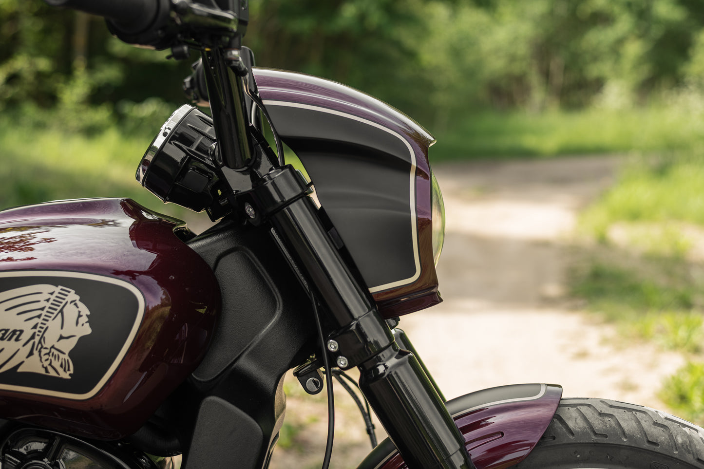 Zoomed Harley Davidson motorcycle with Killer Custom "Tomahawk" series headlight fairing from the side in the forest blurry background