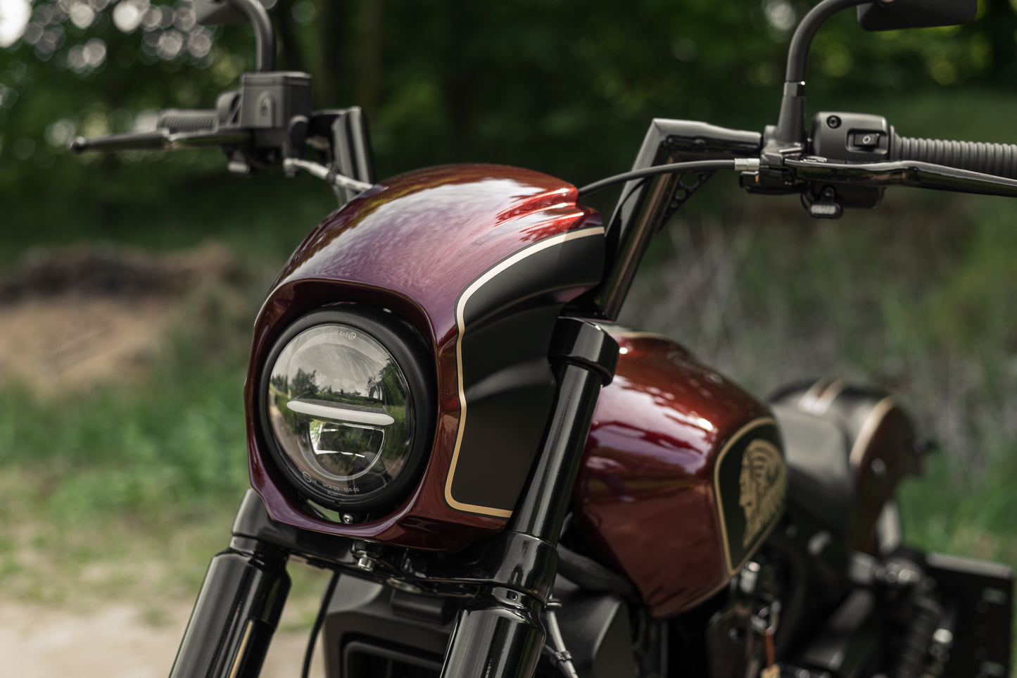 Zoomed Harley Davidson motorcycle with Killer Custom  "Tomahawk" series headlight fairing from the front green blurry background