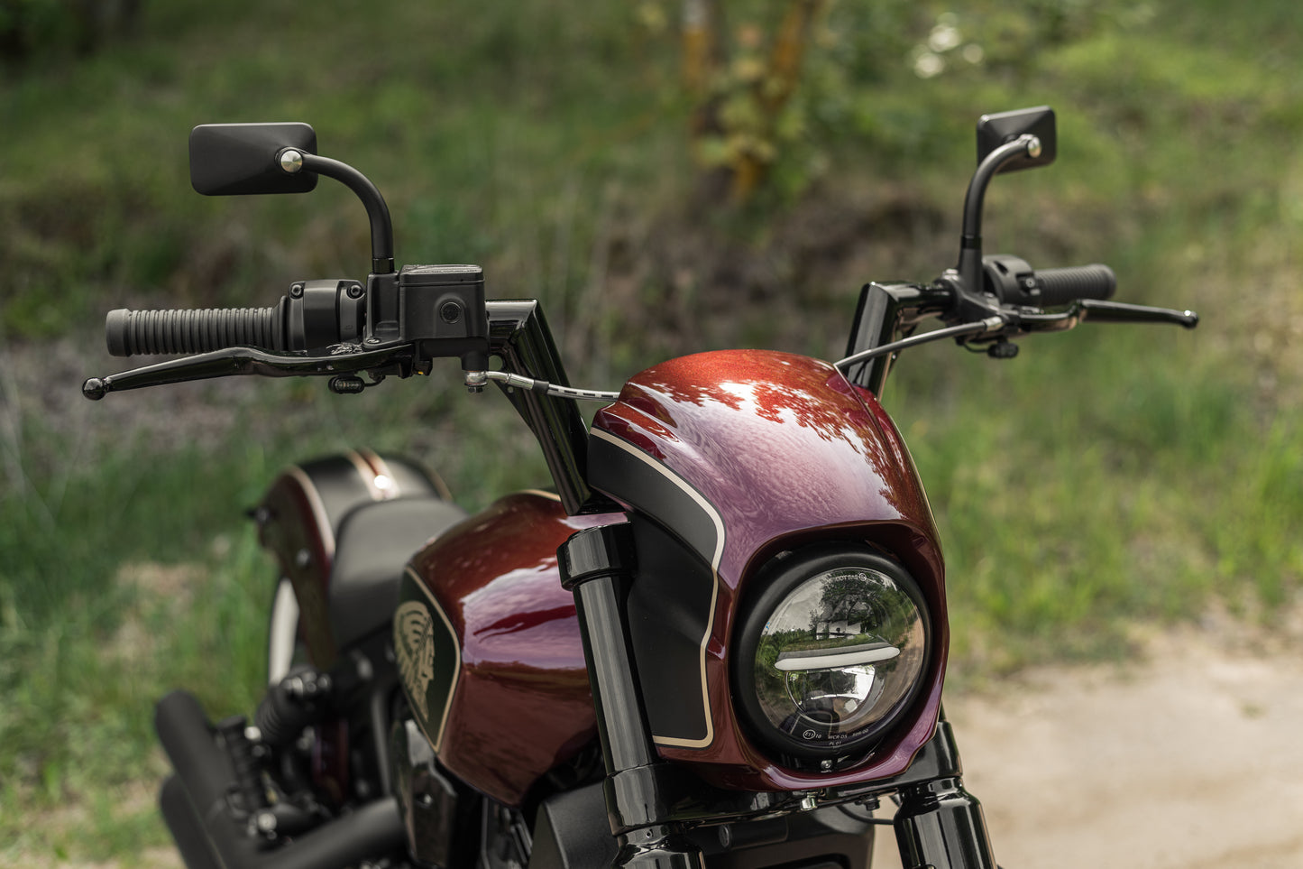 Harley Davidson motorcycle with Killer Custom "Tomahawk" series mini ape handlebar from the front with a green blurred background