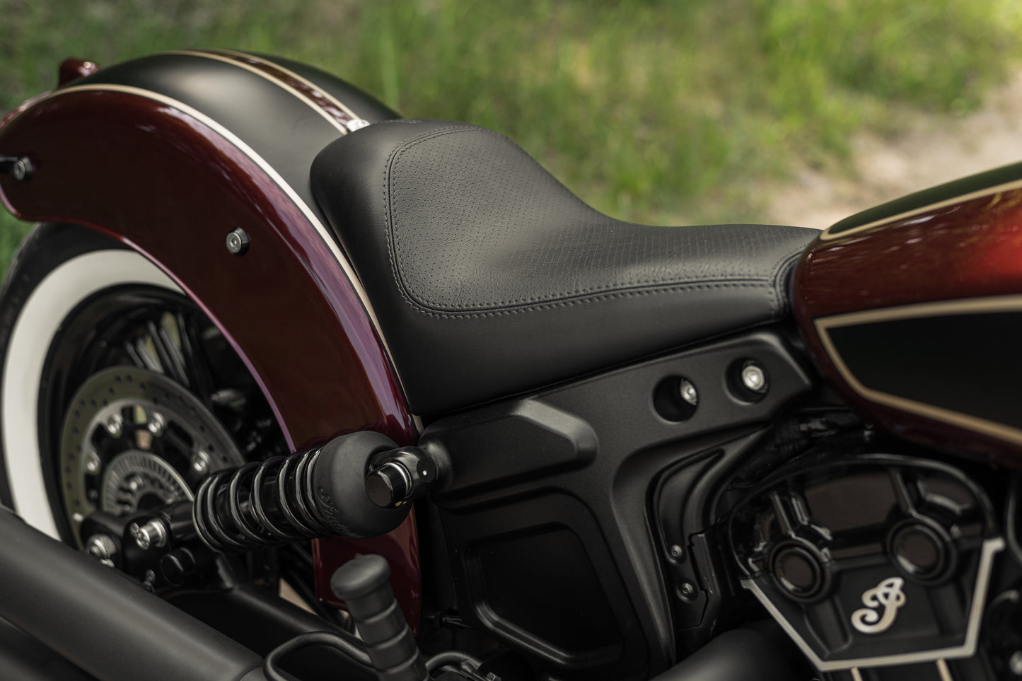 Harley Davidson motorcycle with Killer Custom Indian scout solo seat from the side green blurry background