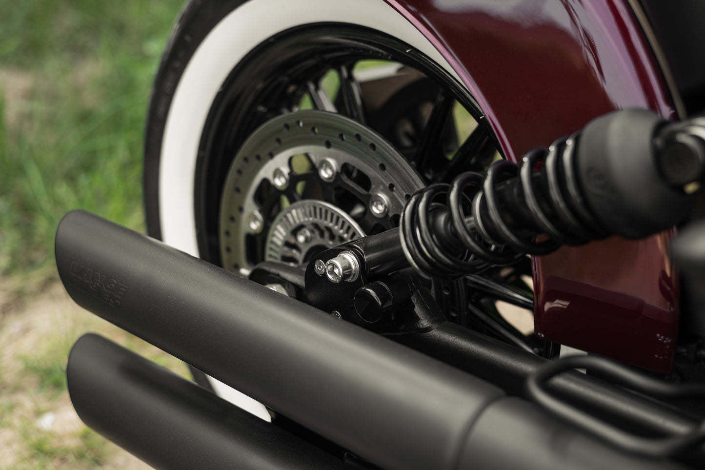 Zoomed Harley Davidson motorcycle with Killer Custom rear shock lowering kit from the side green blurry background
