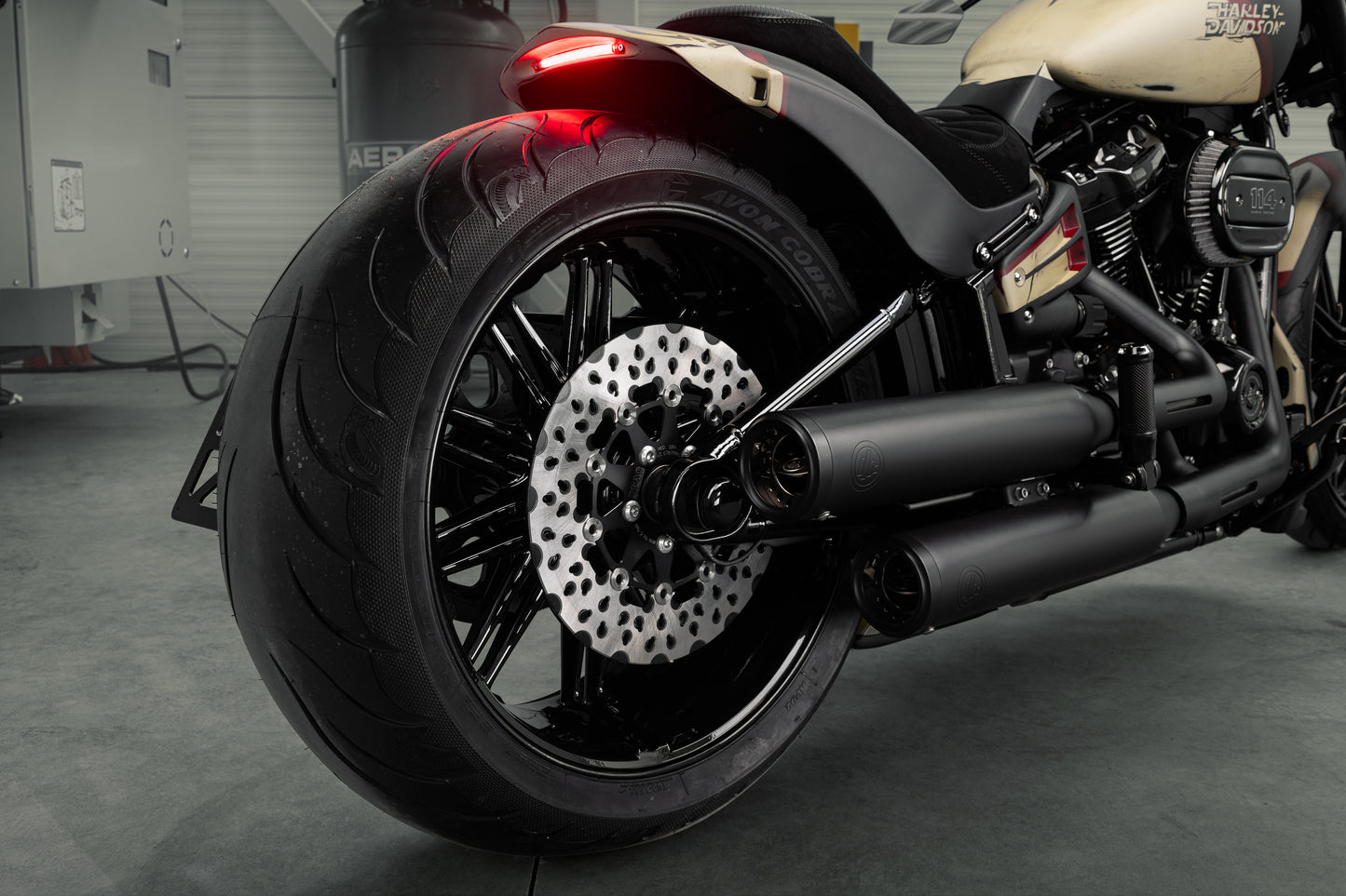 Zoomed Harley Davidson motorcycle with Killer Custom "Avenger" rear fender kit from the rear in a modern bike shop