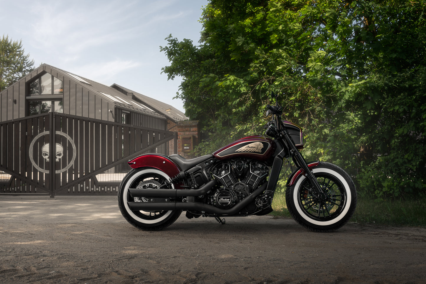 Harley Davidson motorcycle with Killer Custom Indian scout solo seat from the side outside on a sunny day with a building and some trees in the background