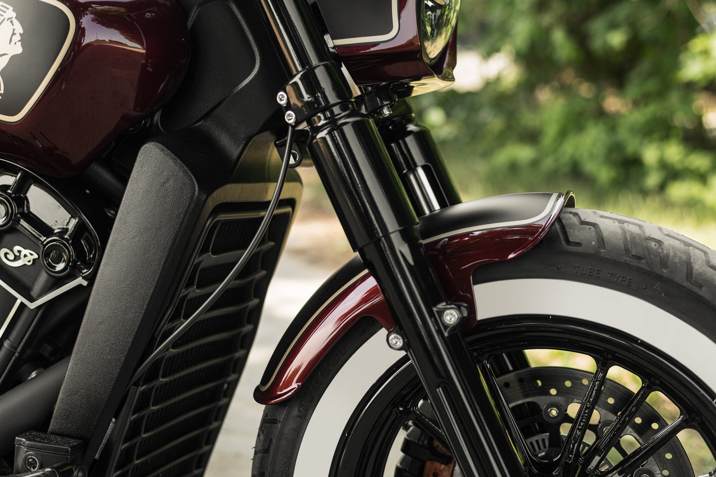 Zoomed Harley Davidson motorcycle with Killer Custom "Apache" series front fender from the side green blurry background