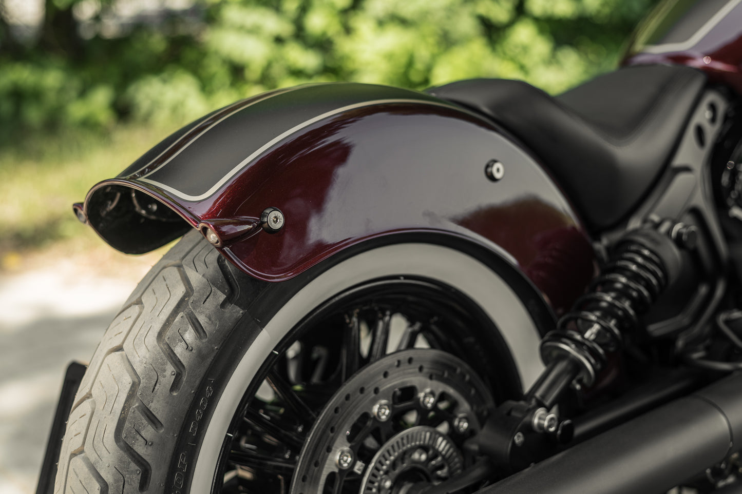 Zoomed Harley Davidson motorcycle with Killer Custom "Apache II" rear fender blurry green background