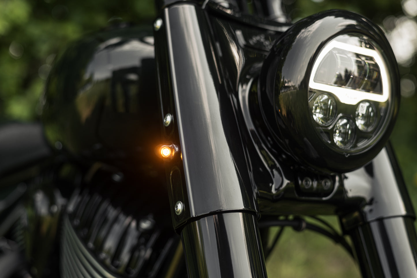 Zoomed Harley Davidson motorcycle with Killer Custom "Mohawk" front led turn signals green blurry background