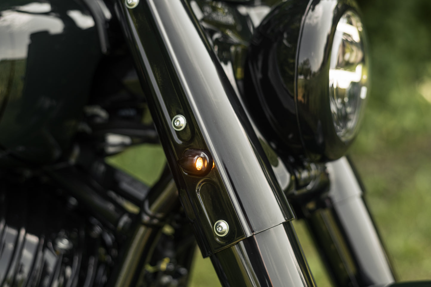 Zoomed Harley Davidson motorcycle with Killer Custom "Mohawk" front led turn signals green blurry background