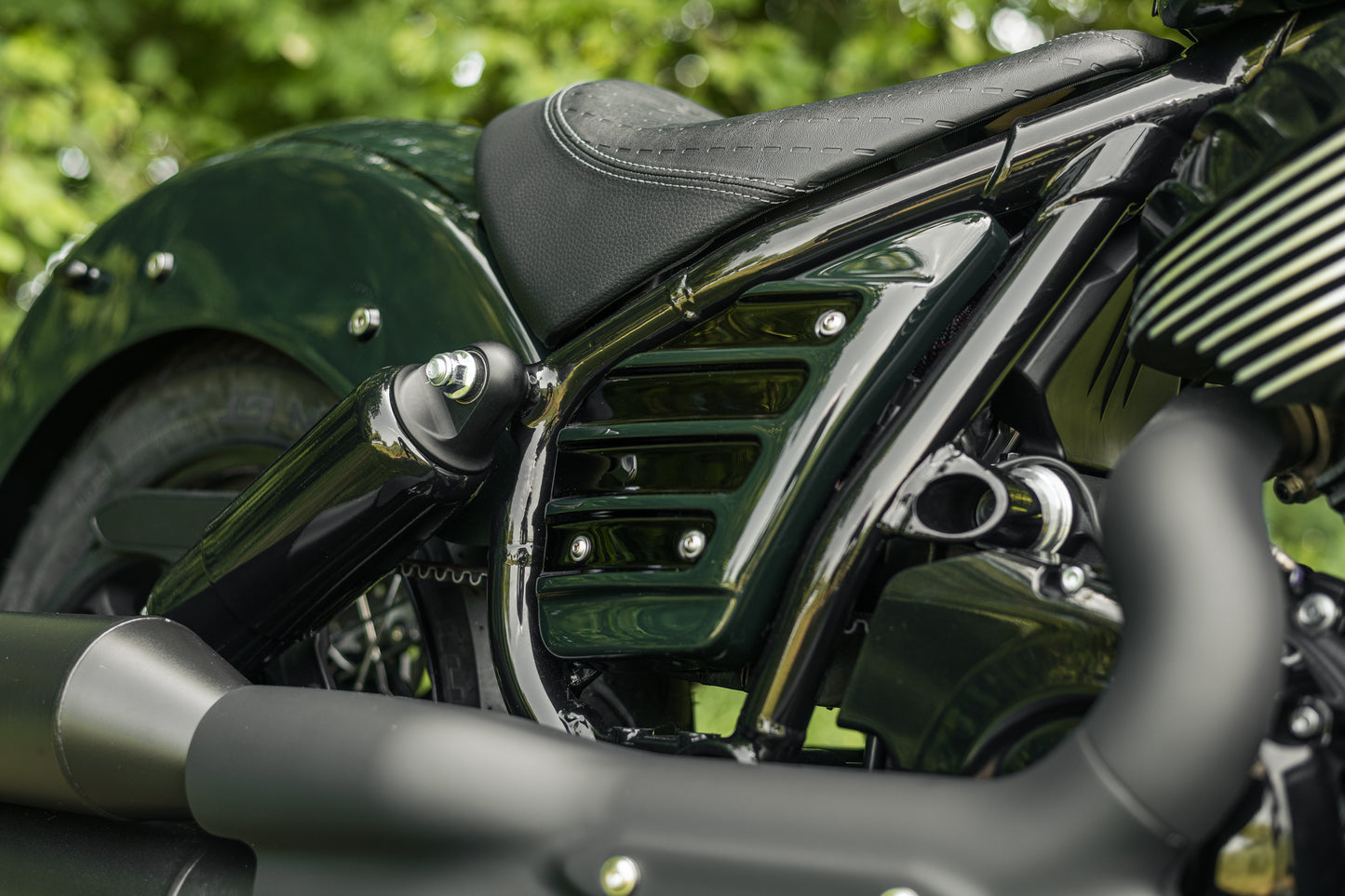 Zoomed Harley Davidson motorcycle with Killer Custom "Apache" side covers from the side green blurry background