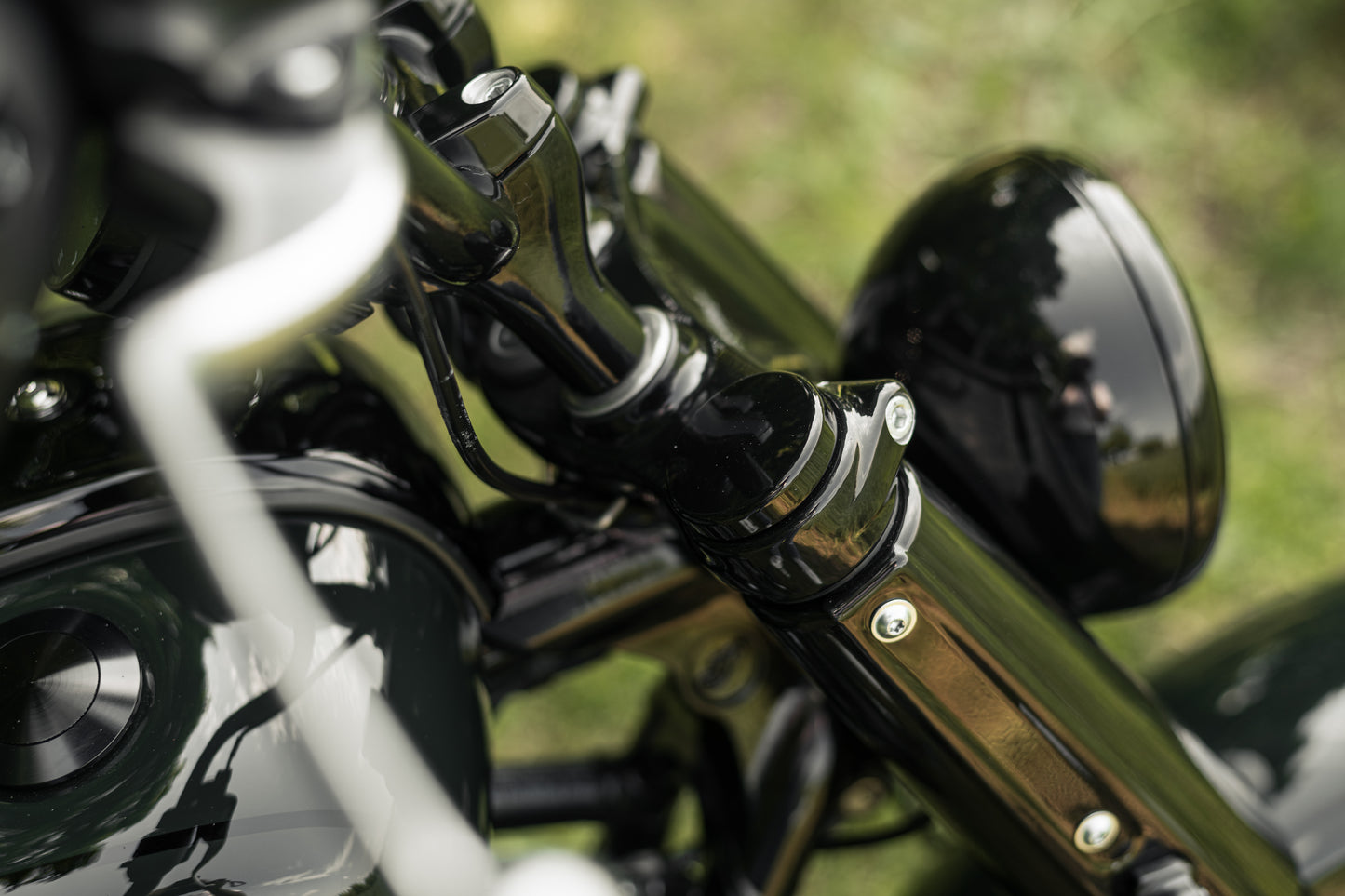 Zoomed Harley Davidson motorcycle with Killer Custom bobber fork caps green blurry background