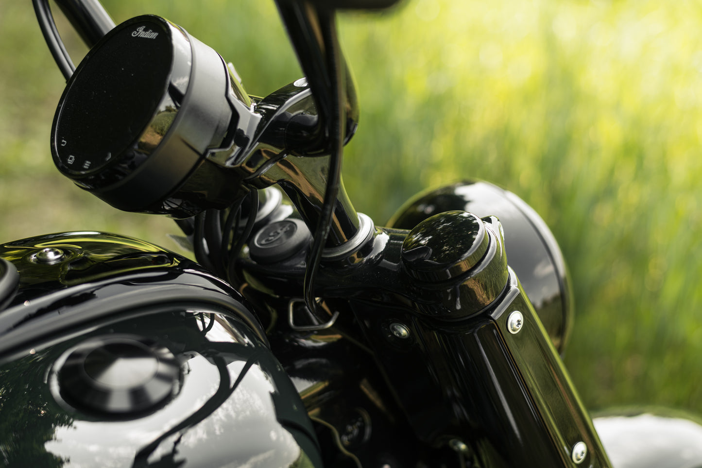 Zoomed Harley Davidson motorcycle with Killer Custom bobber fork caps green blurry background