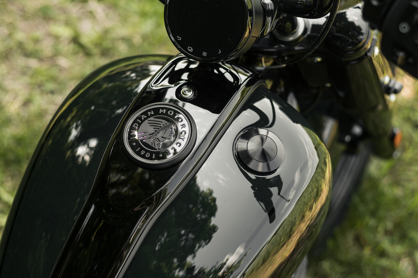 Zoomed Harley Davidson motorcycle with Killer Custom flush mount pop-up gas cap from above with blurred grass in the background