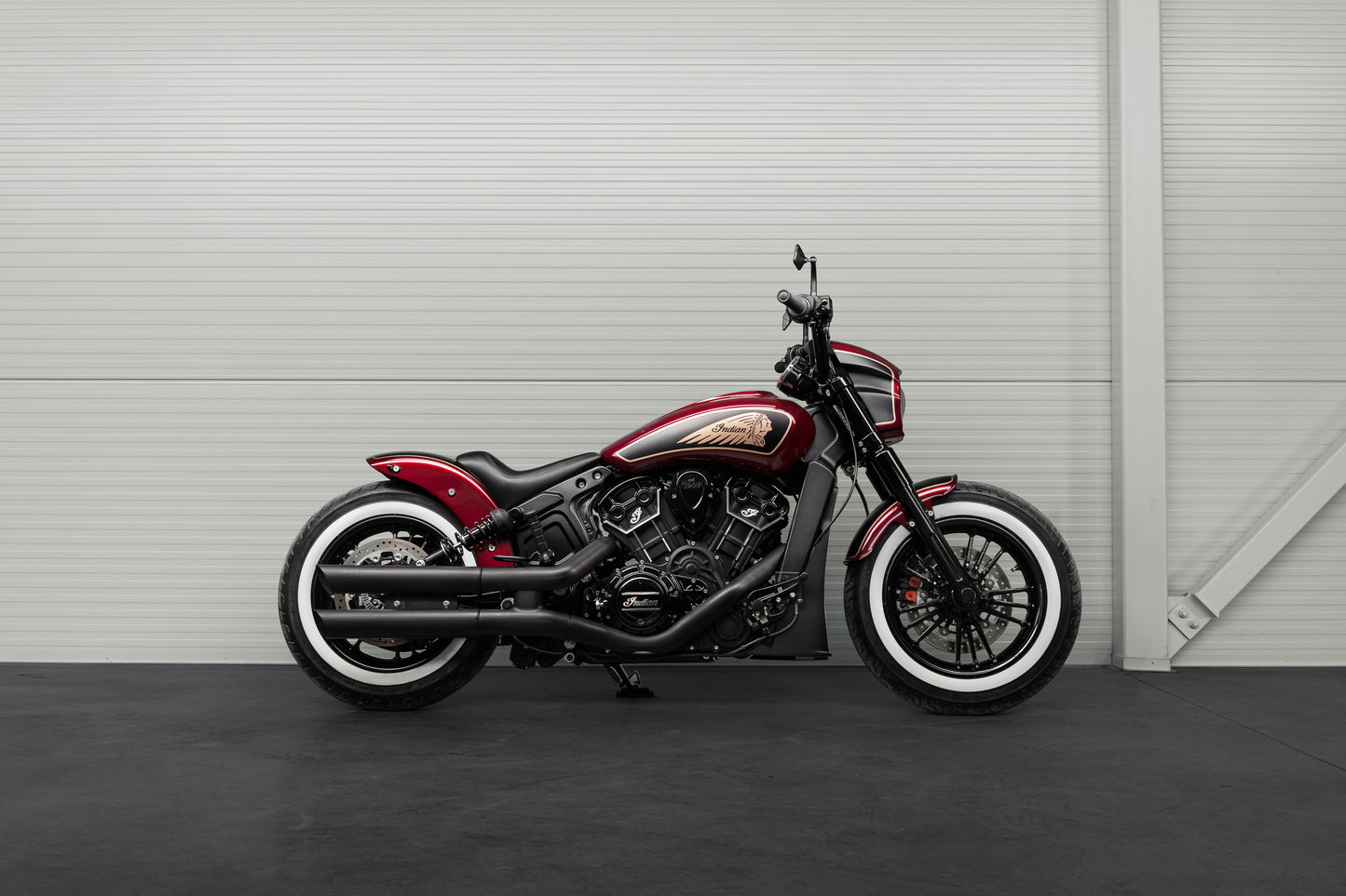 Harley Davidson motorcycle with Killer Custom Indian scout solo seat from the side in a modern garage