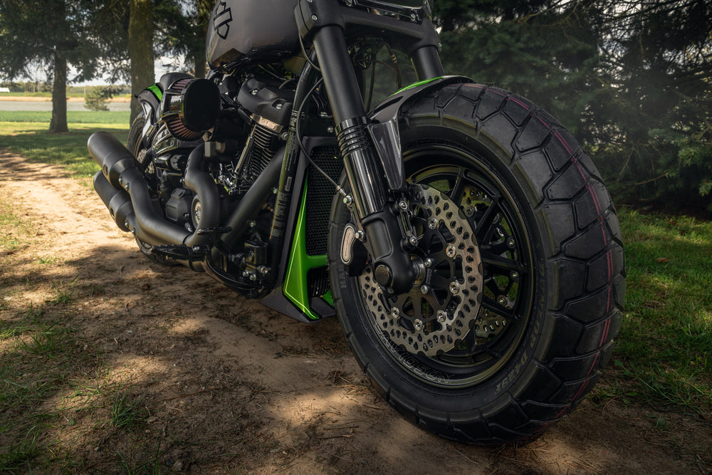 Harley Davidson motorcycle with Killer Custom fat bob and low ride lower fork covers from the front in a nature environment