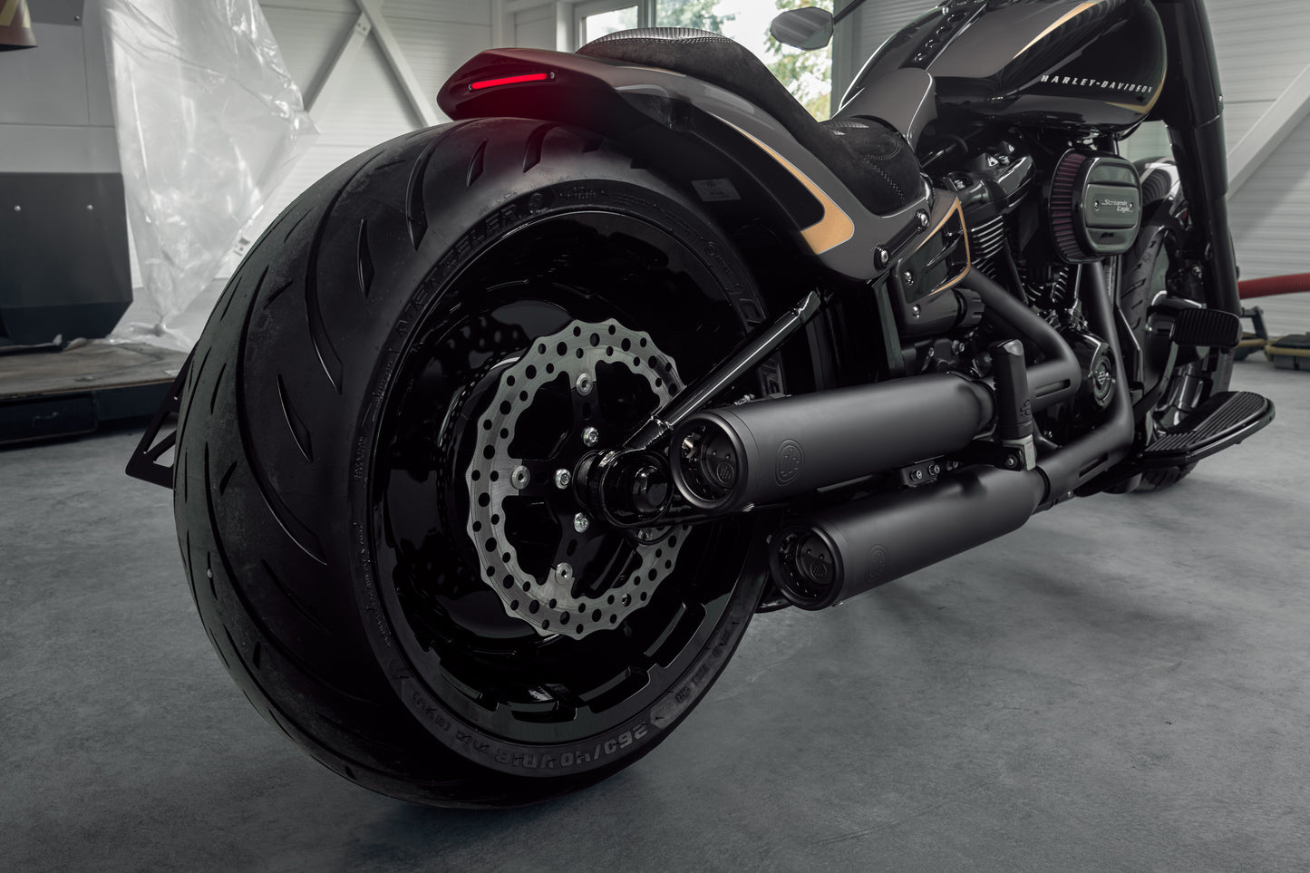 Zoomed Harley Davidson motorcycle with Killer Custom parts from the rear in a modern garage
