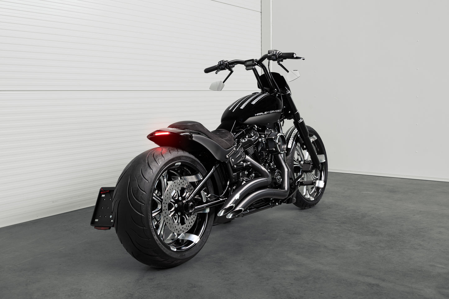  Harley Davidson motorcycle with Killer Custom "Avenger" rear fender kit from the rear in a white modern garage