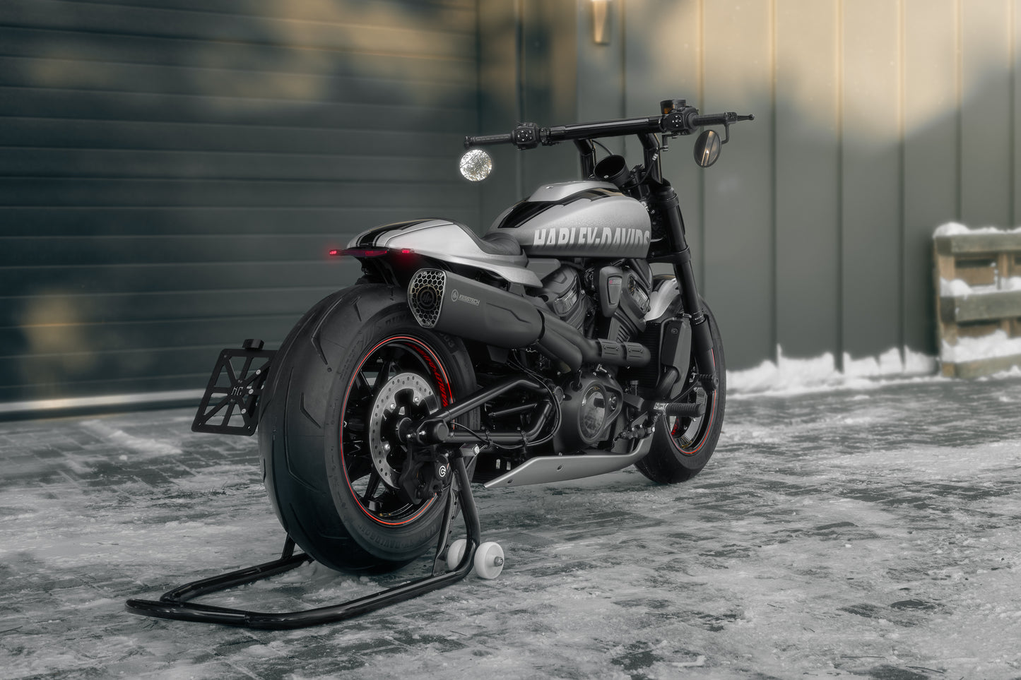 Harley Davidson motorcycle with Killer Custom "Killer Bull" t-bar from the rear outside in front of the modern garage with visible snow on the ground