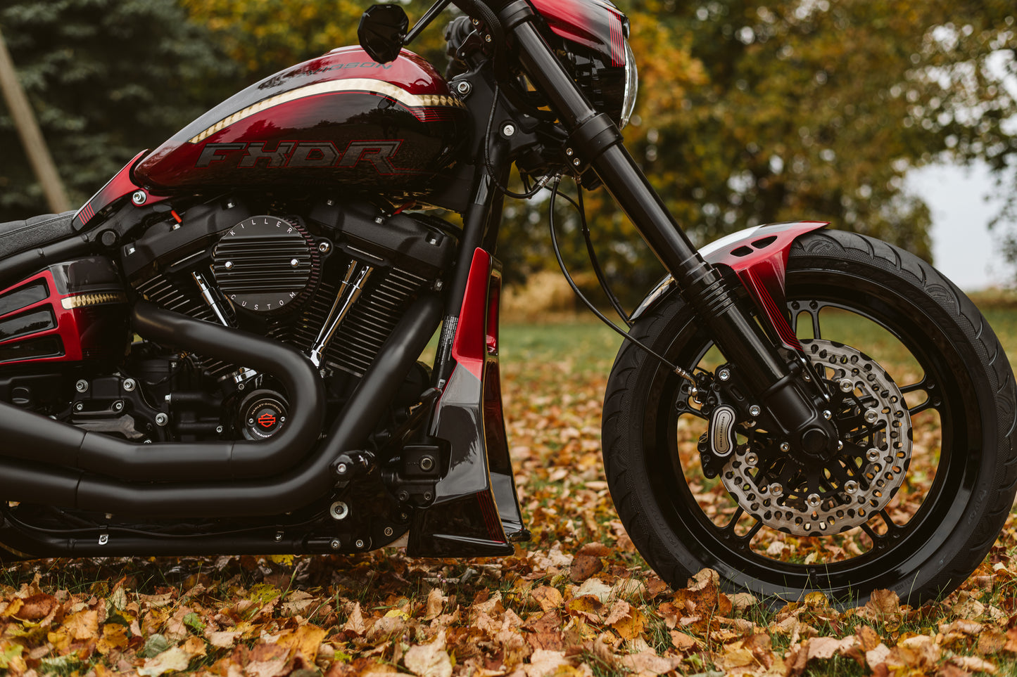Zoomed Harley Davidson motorcycle with Killer Custom lower fork covers from the side outside with fallen leaves in the background