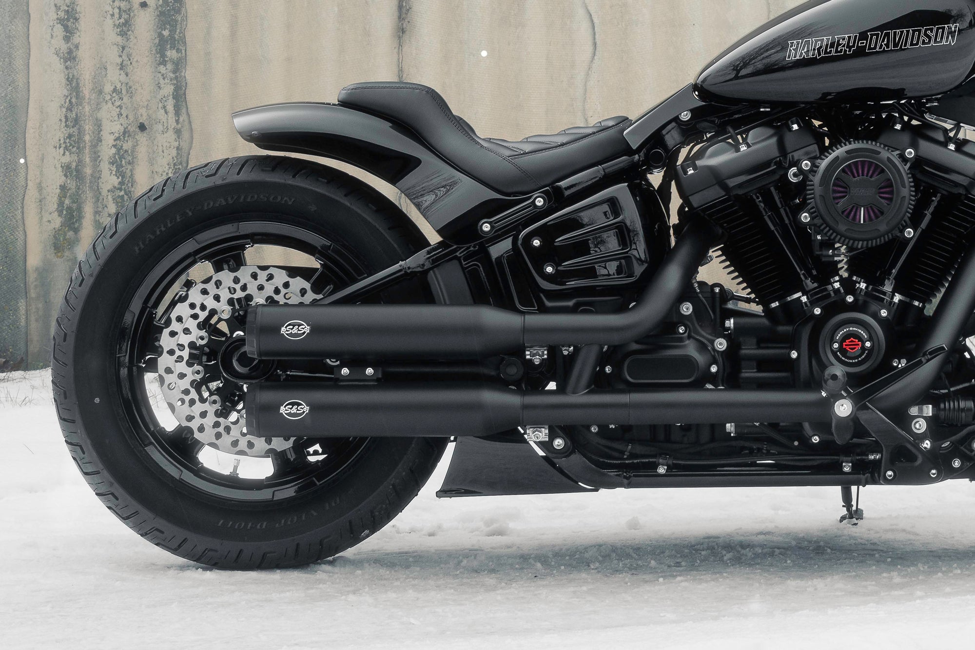 Zoomed Harley Davidson motorcycle with Killer Custom parts from the side with some visible snow on the ground neutral background