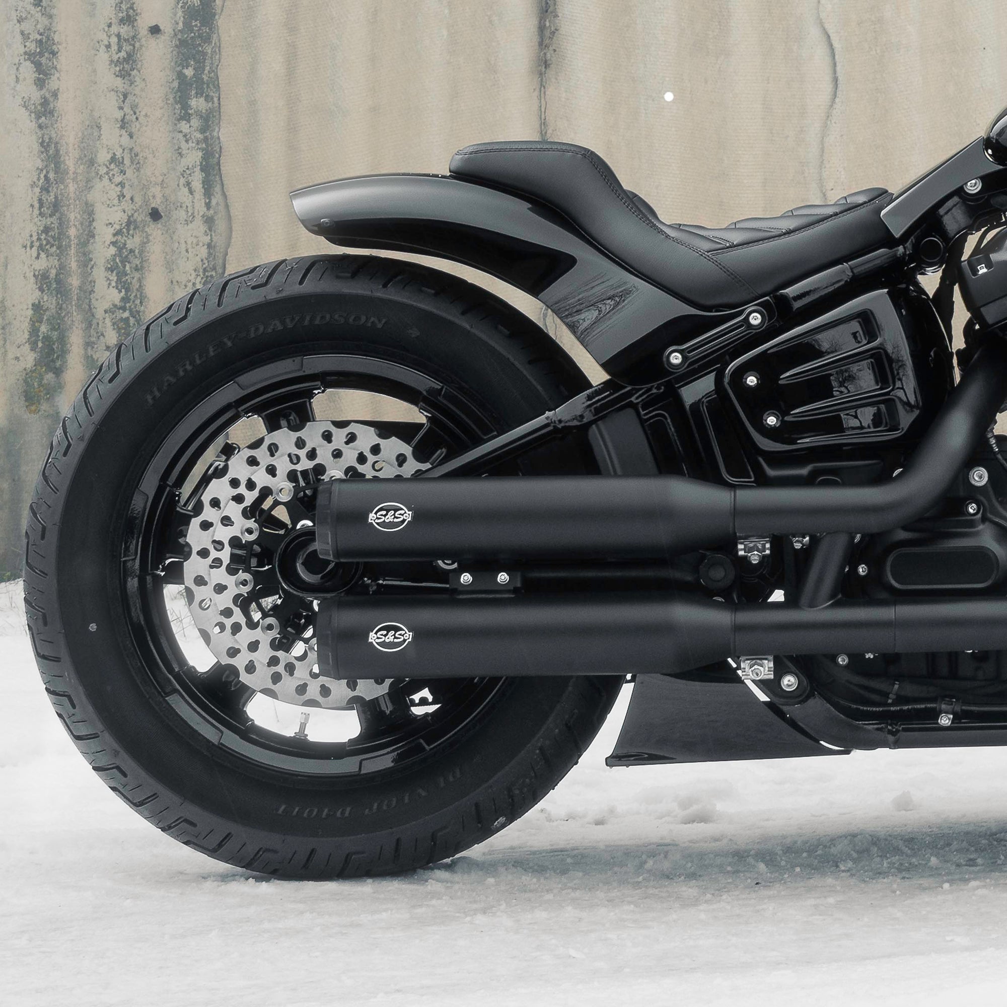 Zoomed Harley Davidson motorcycle with Killer Custom parts from the side outside with some visible snow on the ground neutral background