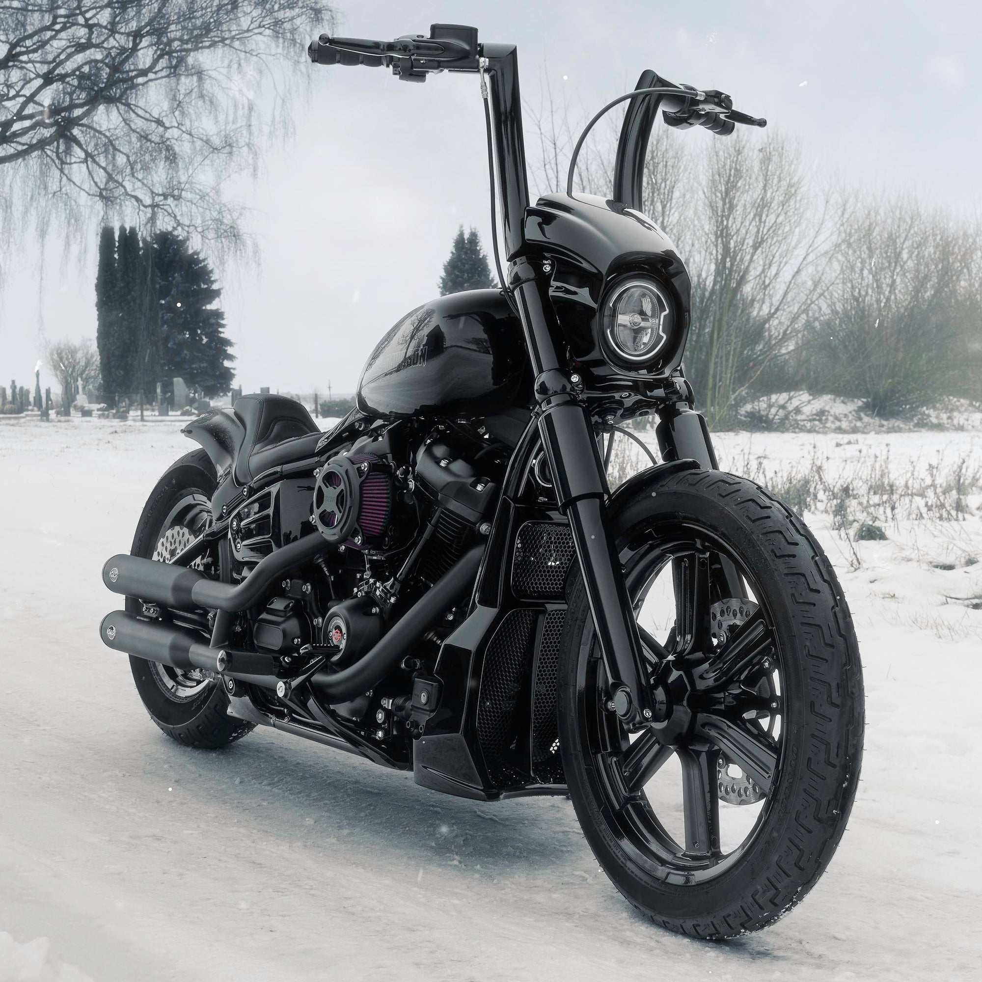 Harley Davidson motorcycle with Killer Custom parts from the front outside on a snowy day with some trees in the background