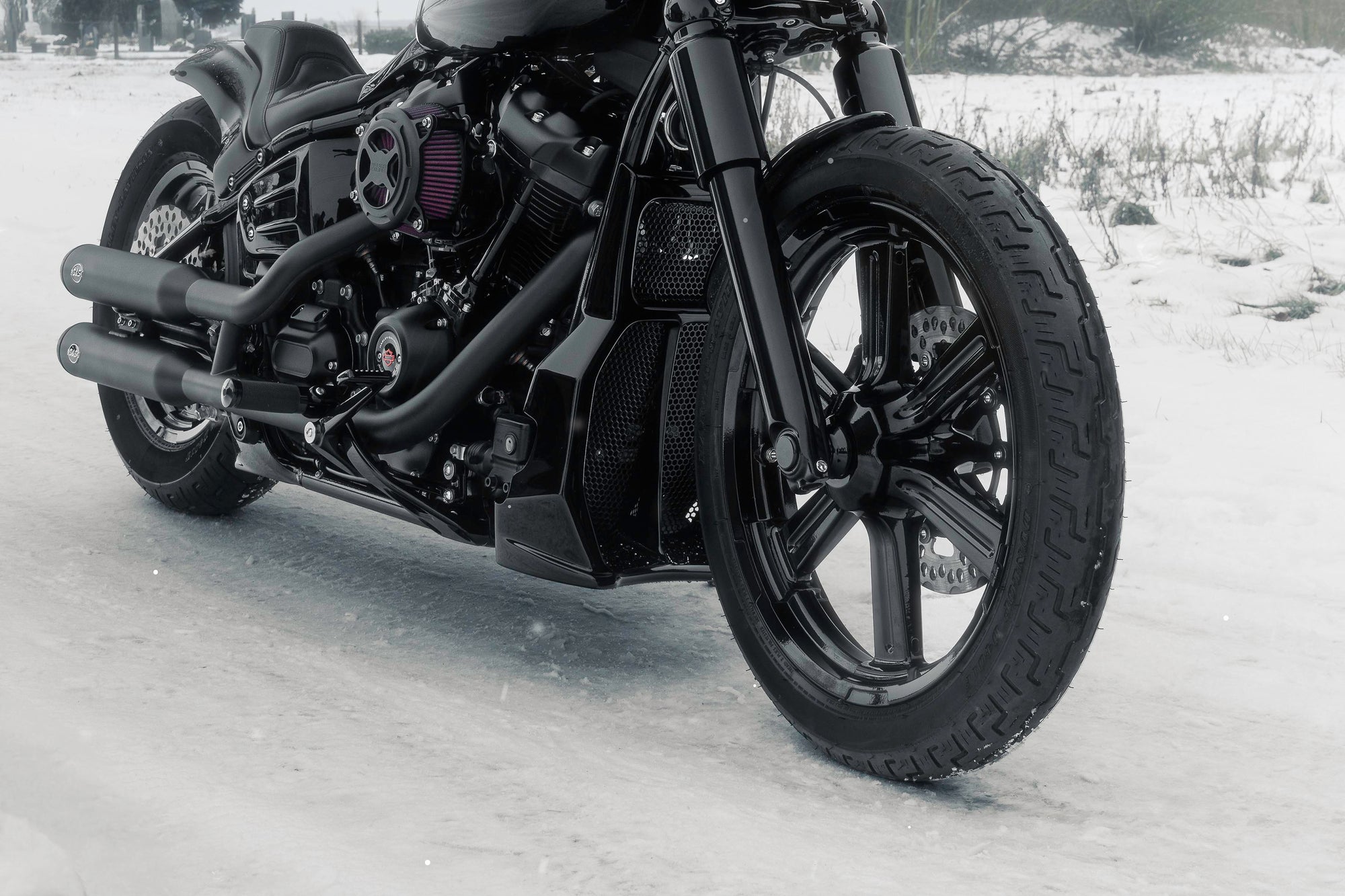 Zoomed Harley Davidson motorcycle with Killer Custom parts from the front outside on a snowy day