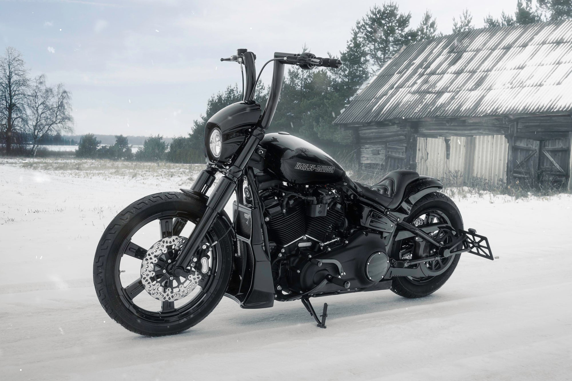 Modified Harley Davidson Softail motorcycle with Killer Custom parts from the side outside on a gloomy winter day with an abandoned shack in the background