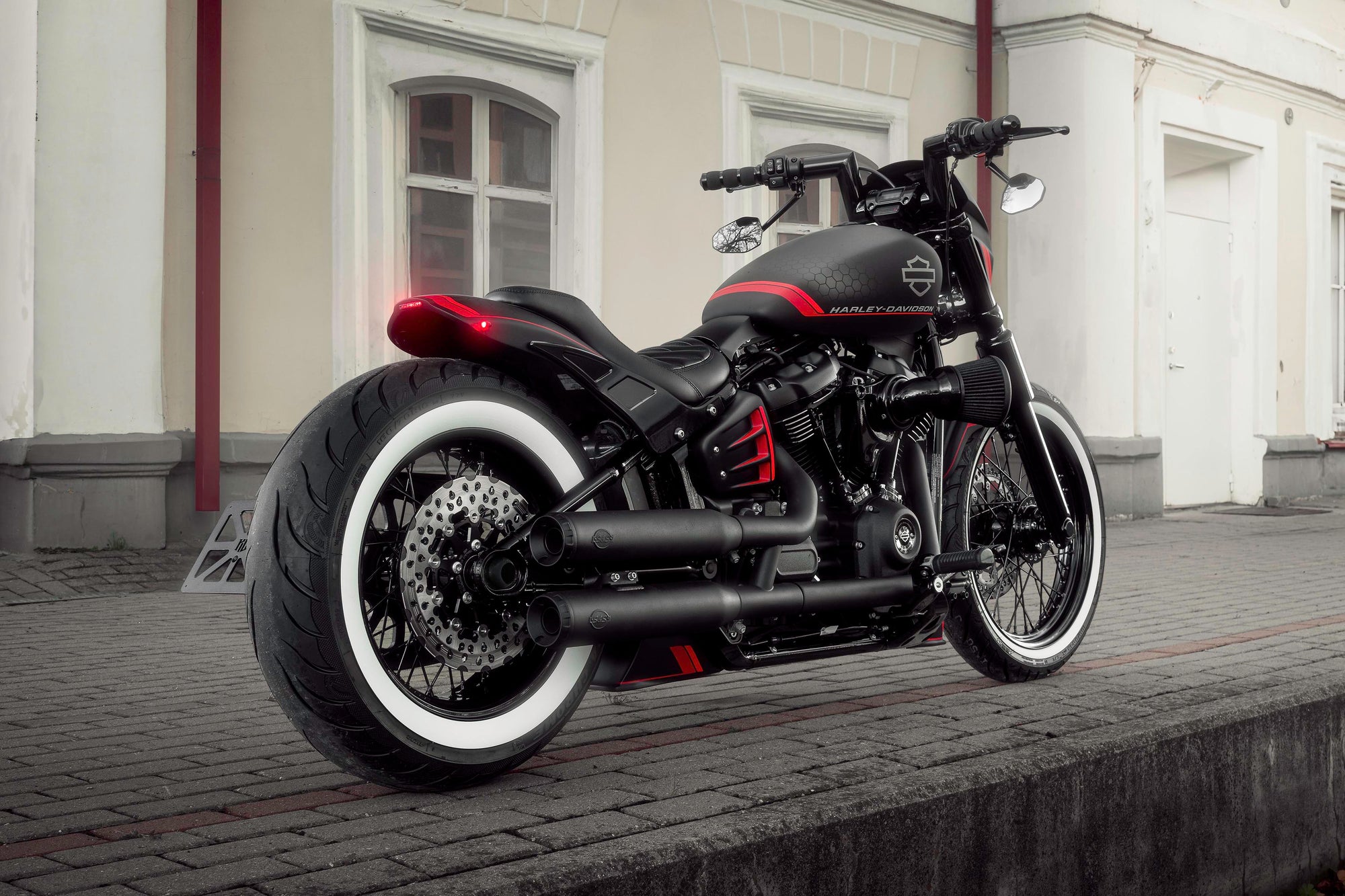 Modified Harley Davidson Street Bob motorcycle with Killer Custom parts from side at a railway station
