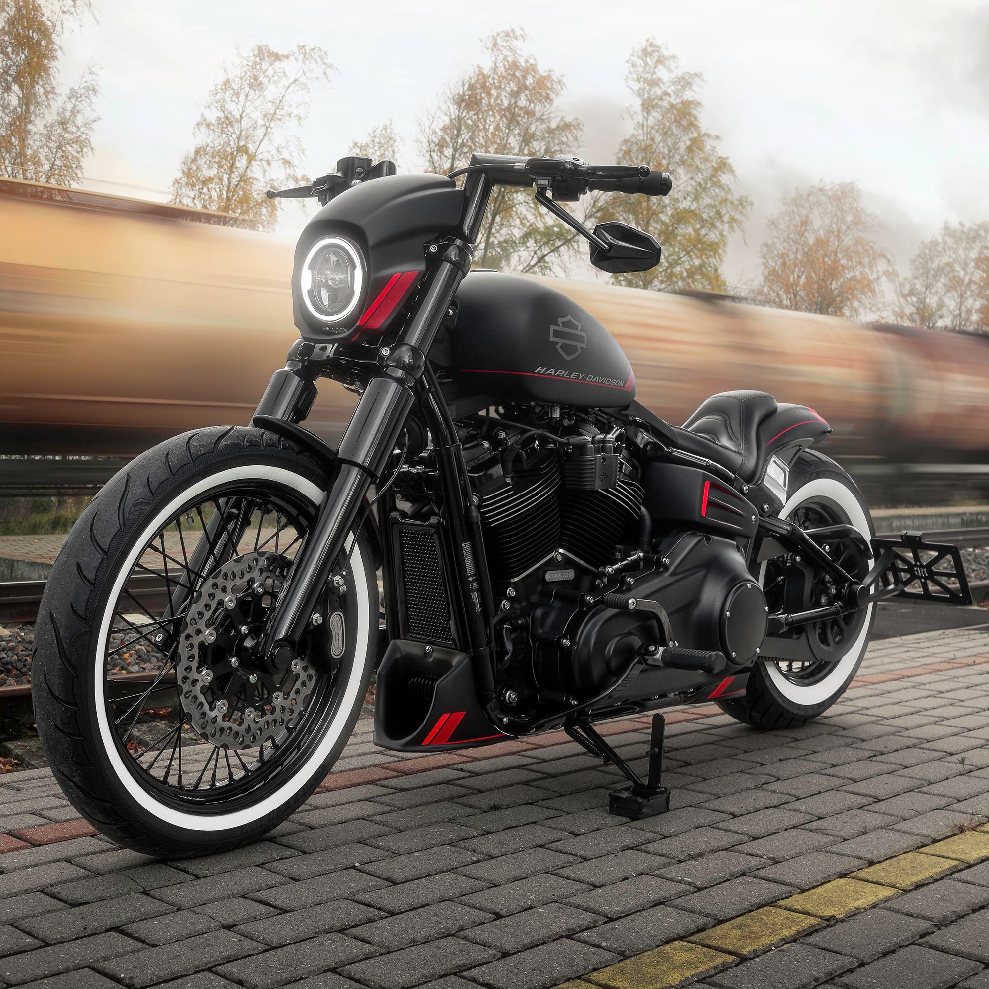 Modified Harley Davidson Street Bob motorcycle with Killer Custom parts from the side at a railway station