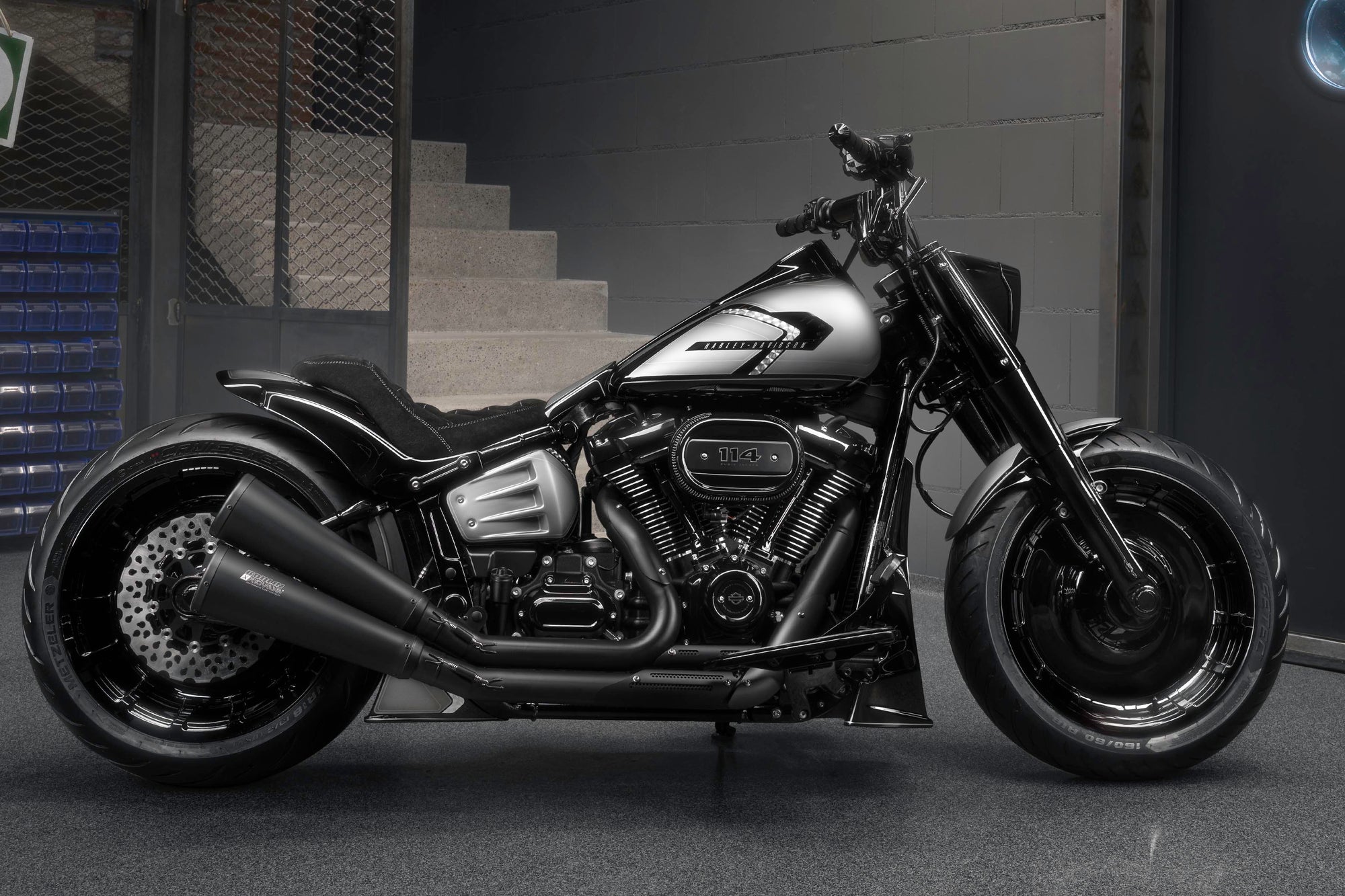 Modified Harley Davidson Softail Fat Boy motorcycle with Killer Custom parts from the side in a modern bike shop