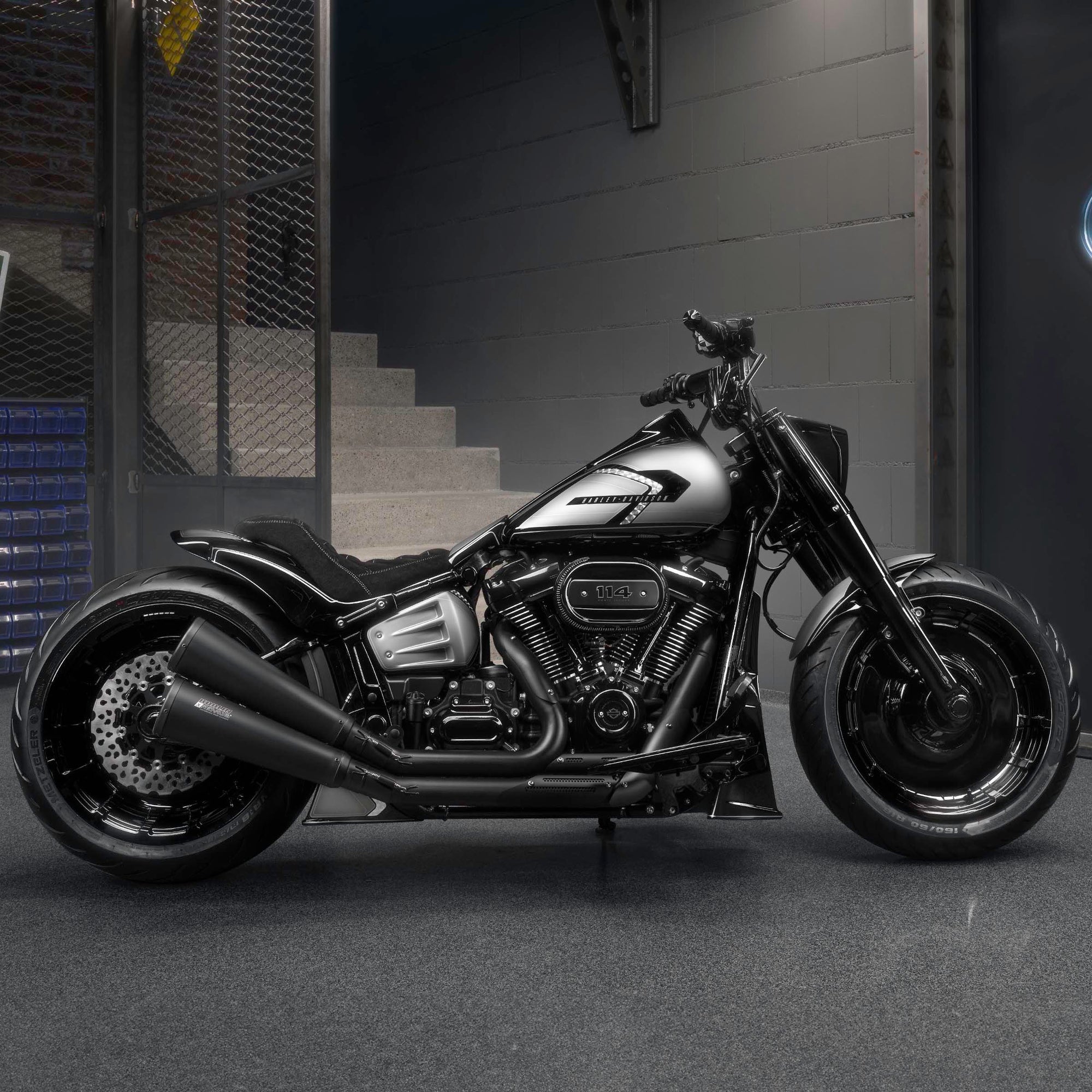 Modified Harley Davidson Softail Fat Boy motorcycle with Killer Custom parts from the side in a modern bike shop