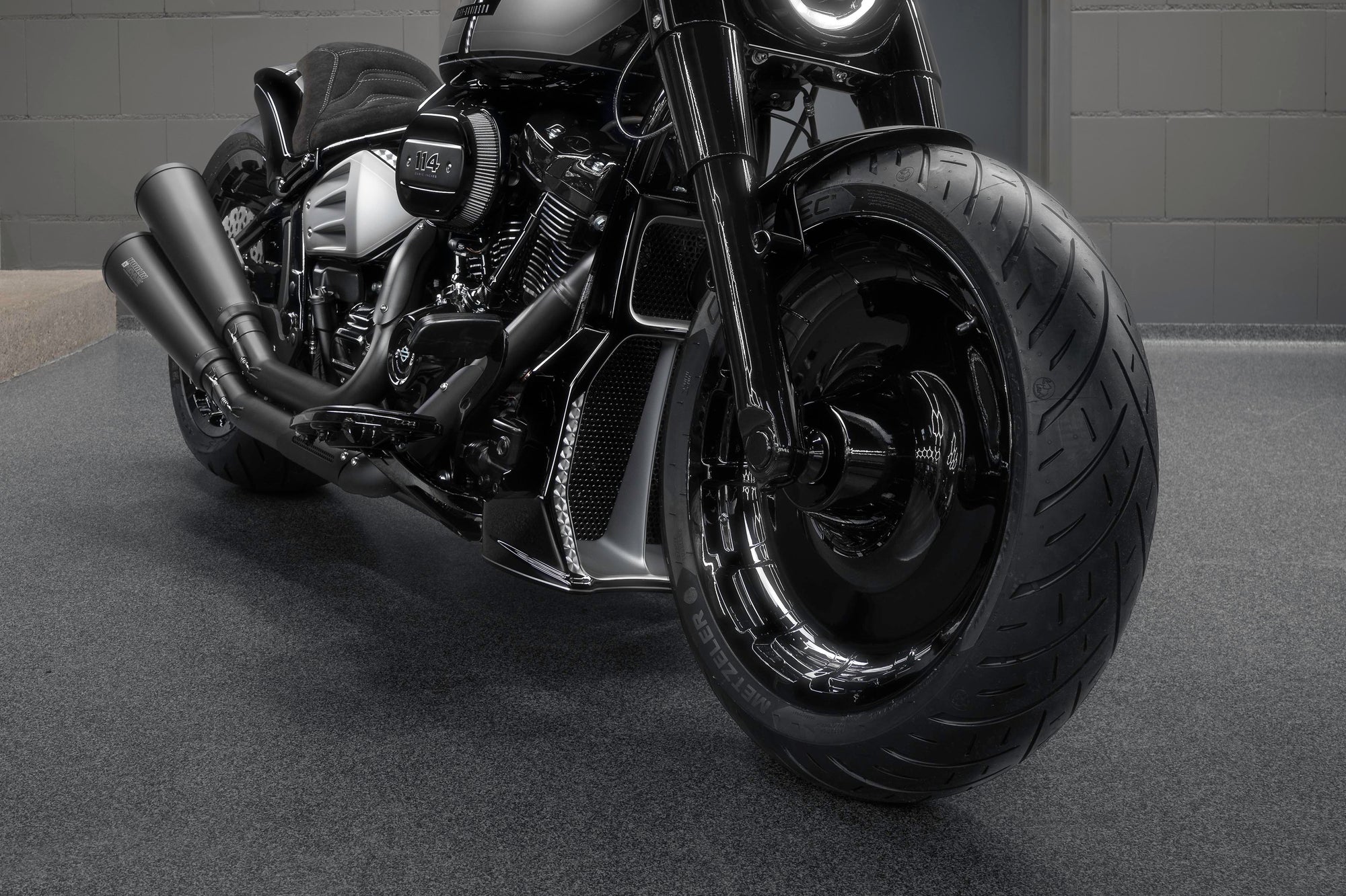 Zoomed Harley Davidson Softail Fat Boy motorcycle with Killer Custom parts from the front in a modern bike shop