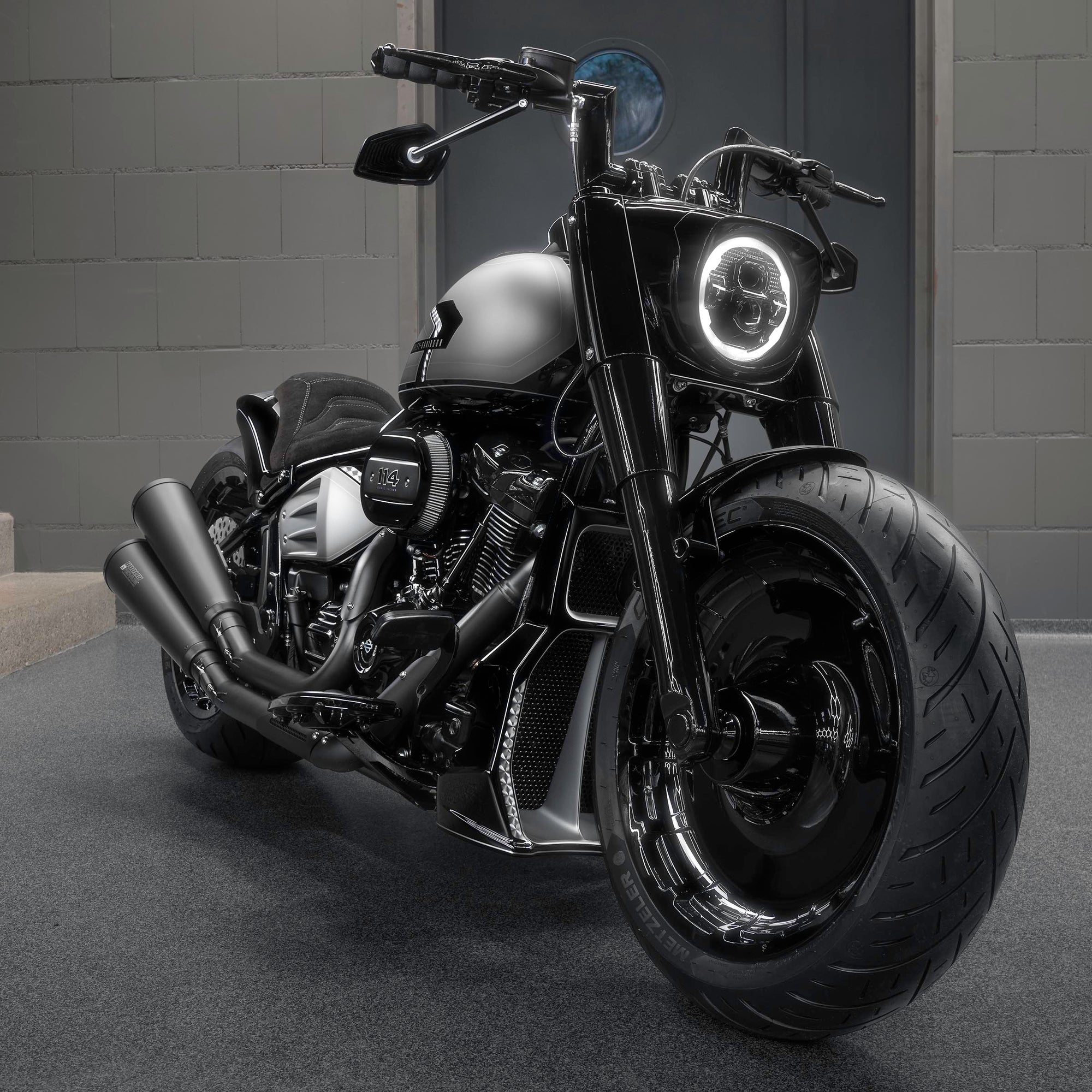 Modified Harley Davidson Softail Fat Boy  motorcycle with Killer Custom parts from the front in a modern bike shop