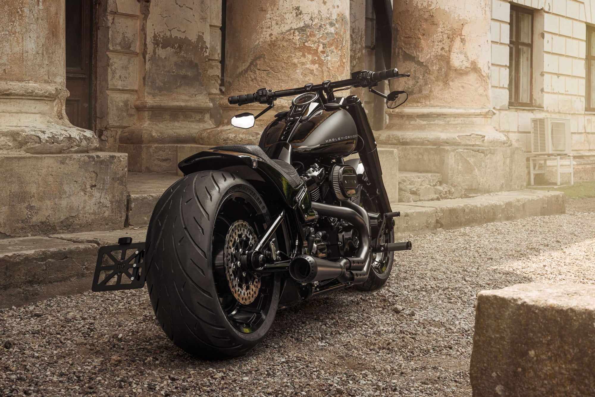 Harley Davidson motorcycle with Killer Custom parts from the rear with an old mansion in the background