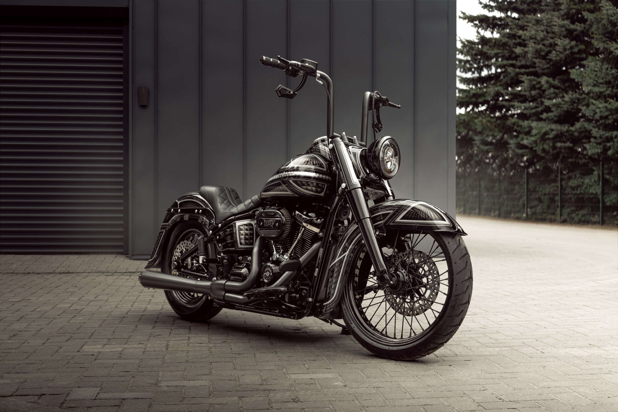 Harley Davidson motorcycle with Killer Custom parts from the side with some trees and a grey wall in the background