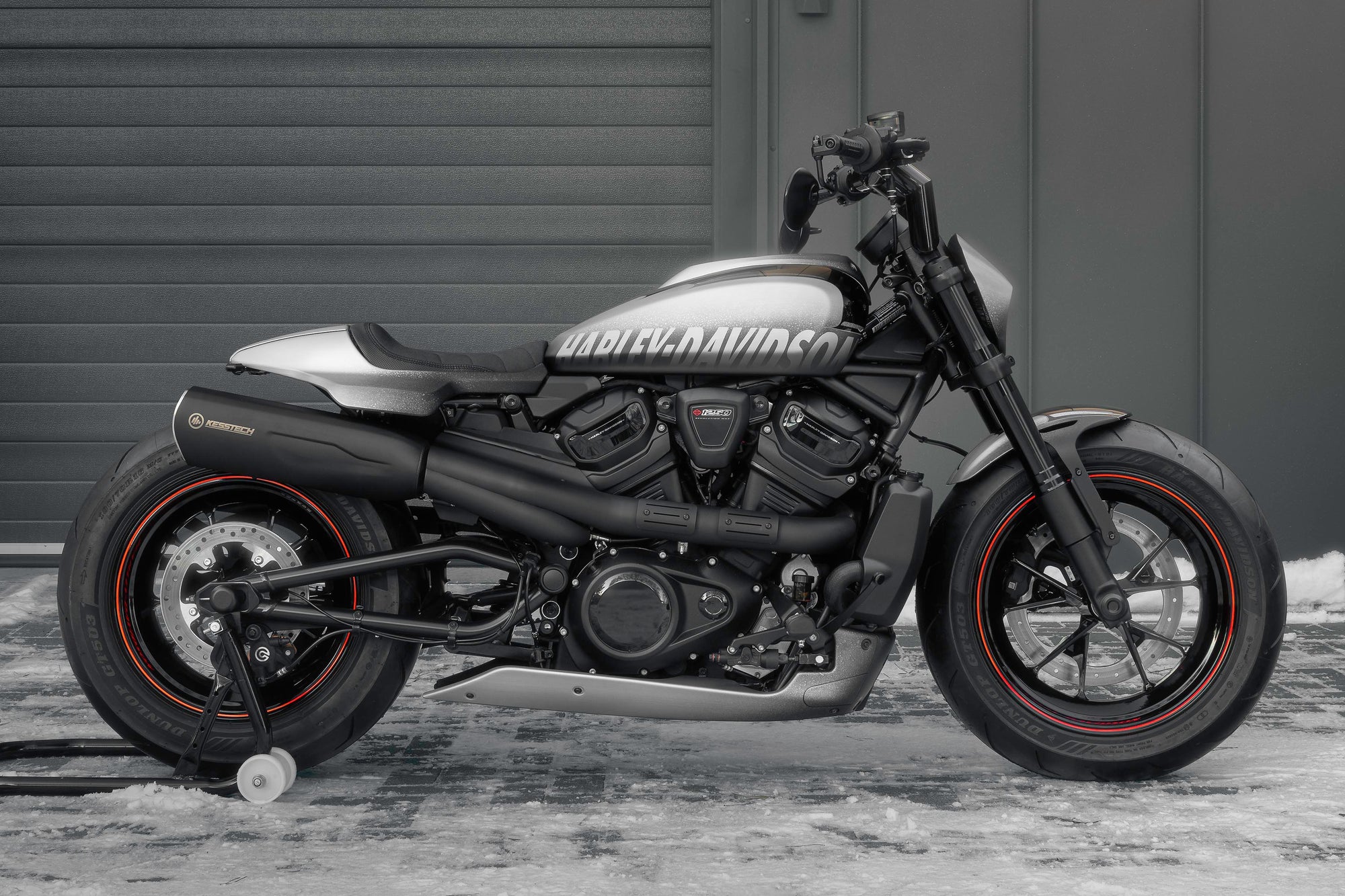 Modified Harley Davidson Sportster S motorcycle with Killer Custom parts from the side outside with some visible snow and a modern garage in the background