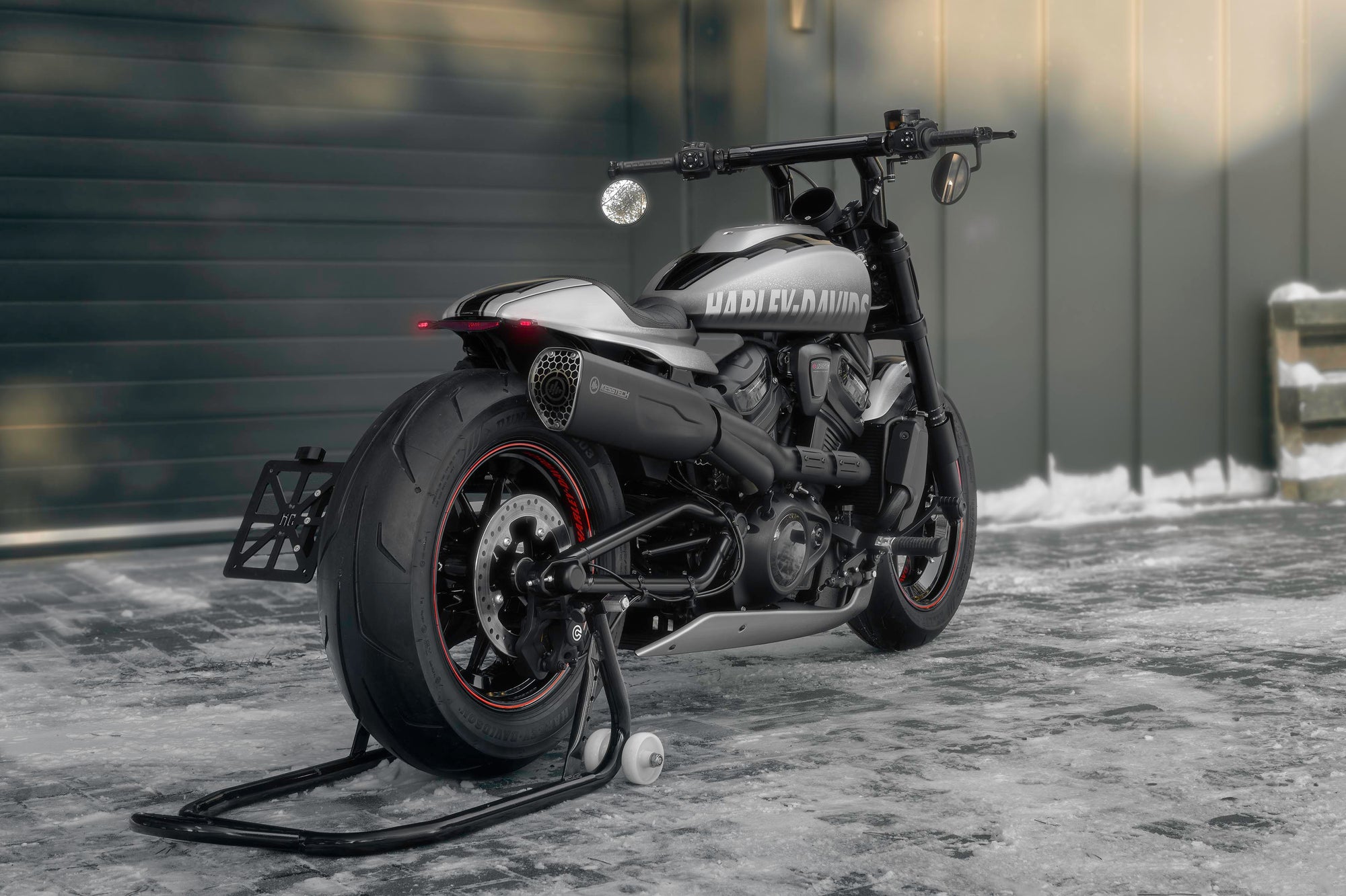 Harley Davidson motorcycle with Killer Custom parts from the side outside with some visible snow and a modern garage in the background