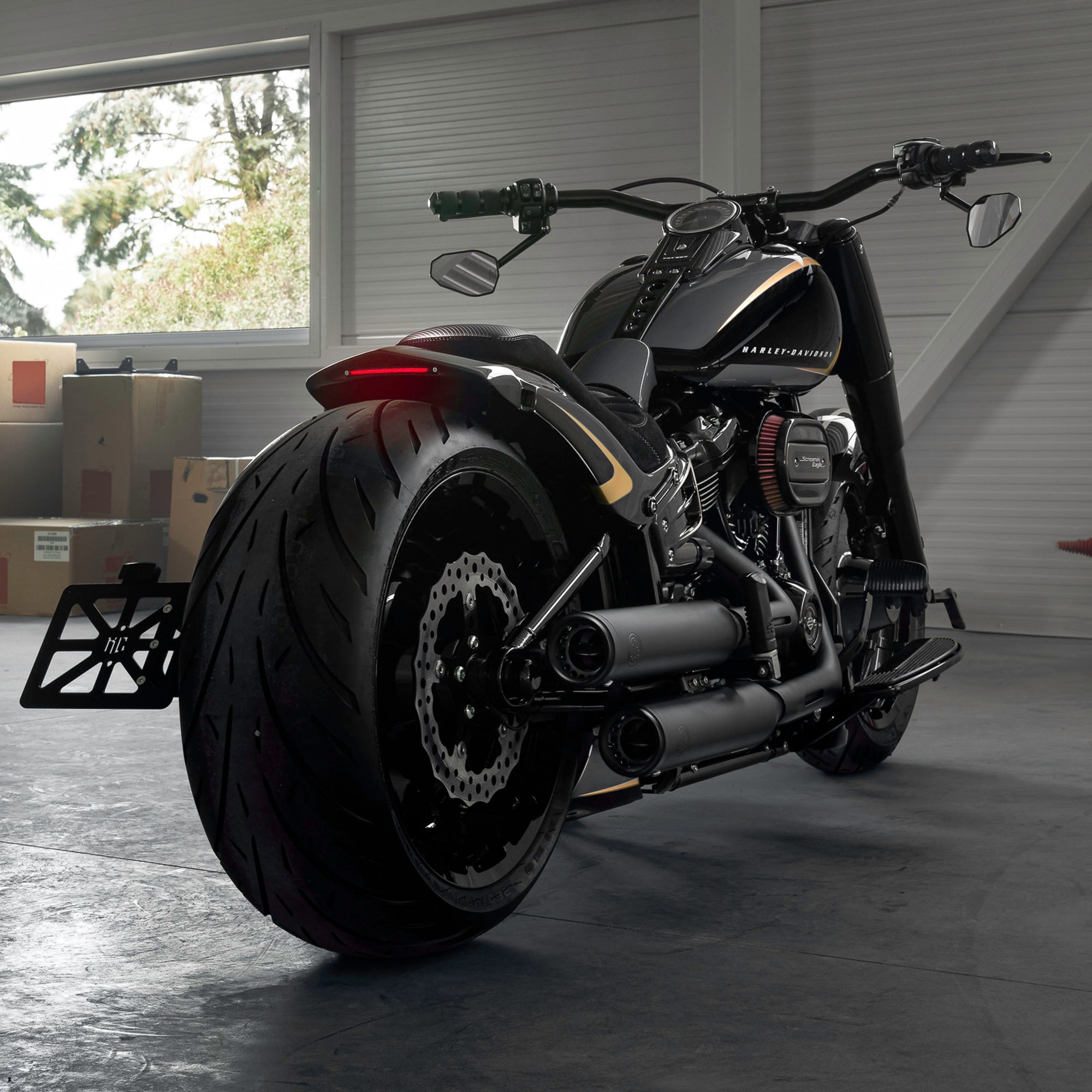 Harley Davidson motorcycle with Killer Custom parts from the rear in a modern garage with some boxes and windows in the background