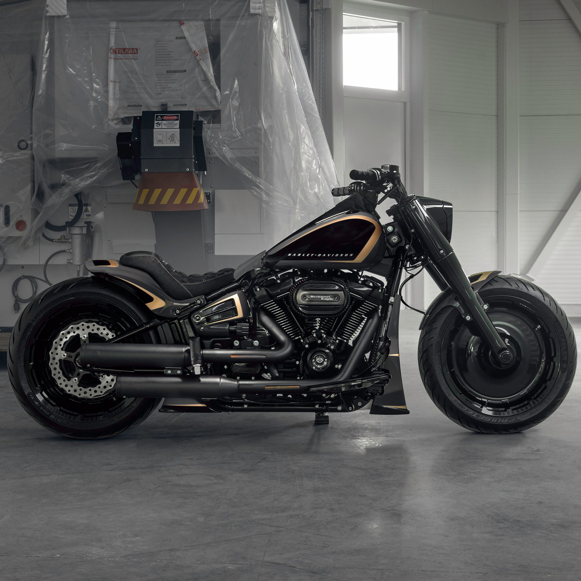 Harley Davidson motorcycle with Killer Custom parts from the side in a modern garage with some equipment in the background