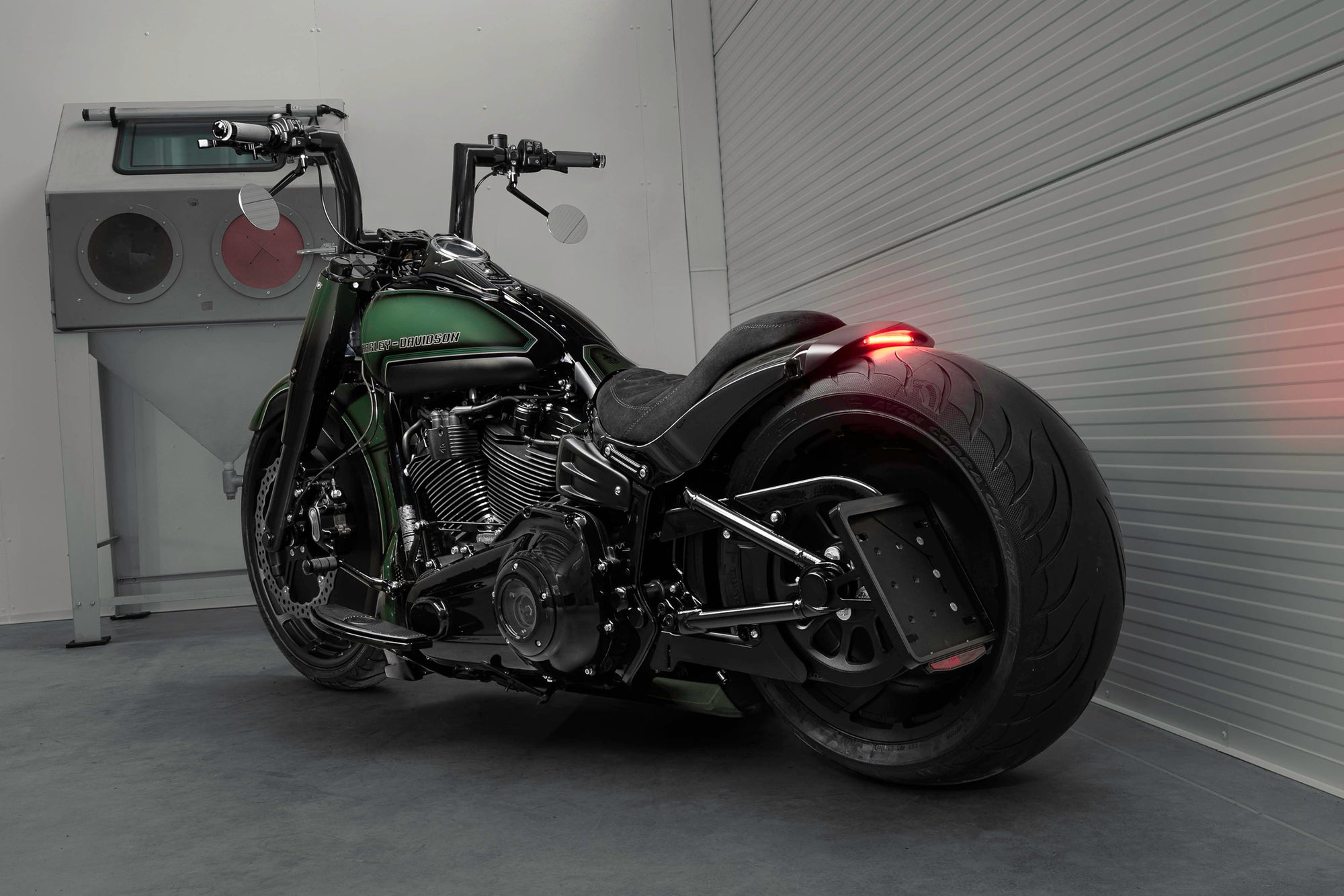 Modified Harley Davidson Fat Boy motorcycle with Killer Custom parts from the side in a spacious and modern garage