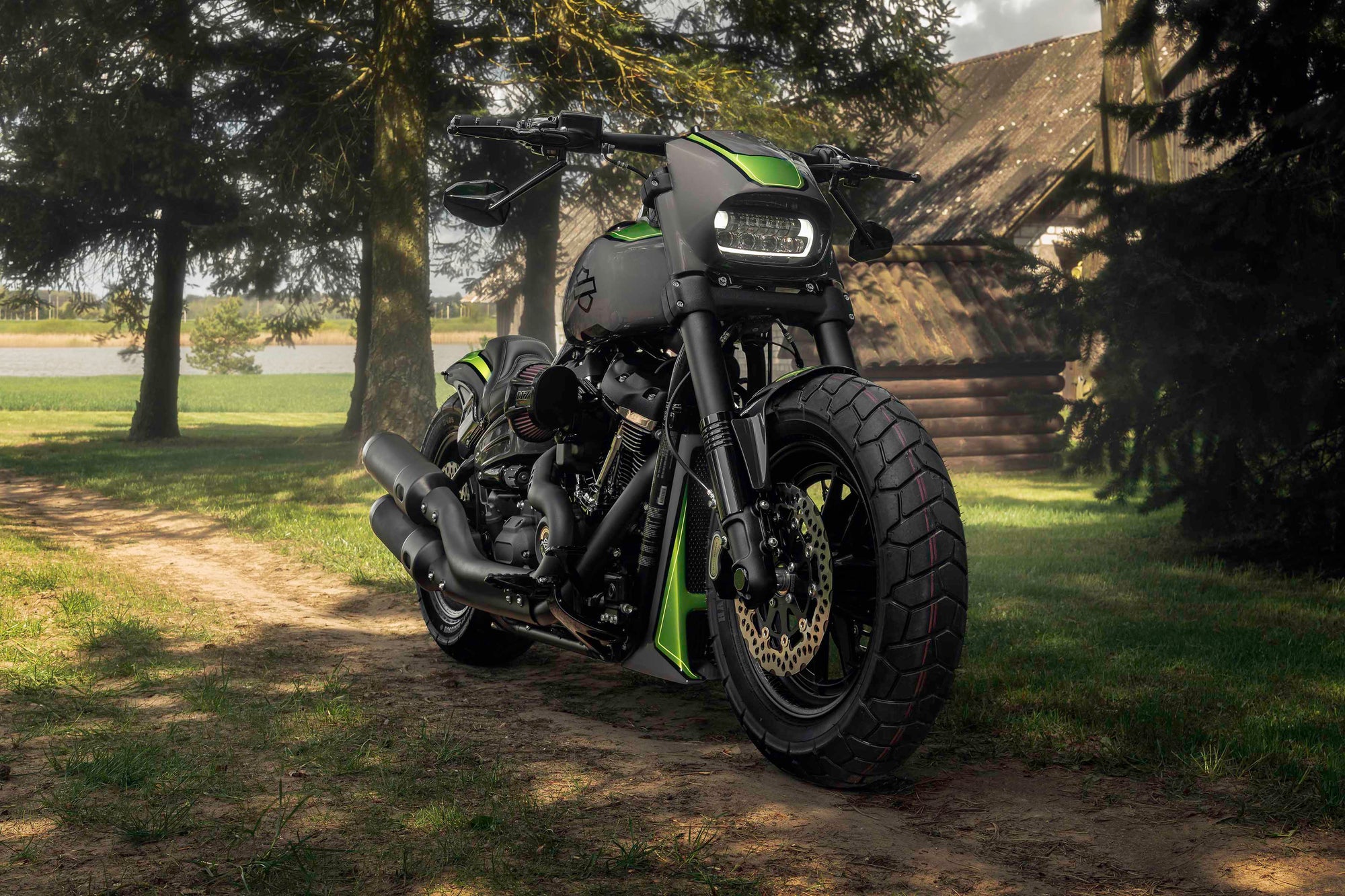 Modified Harley Davidson Fat Bob motorcycle with Killer Custom parts from the front with a country house and some trees in the background
