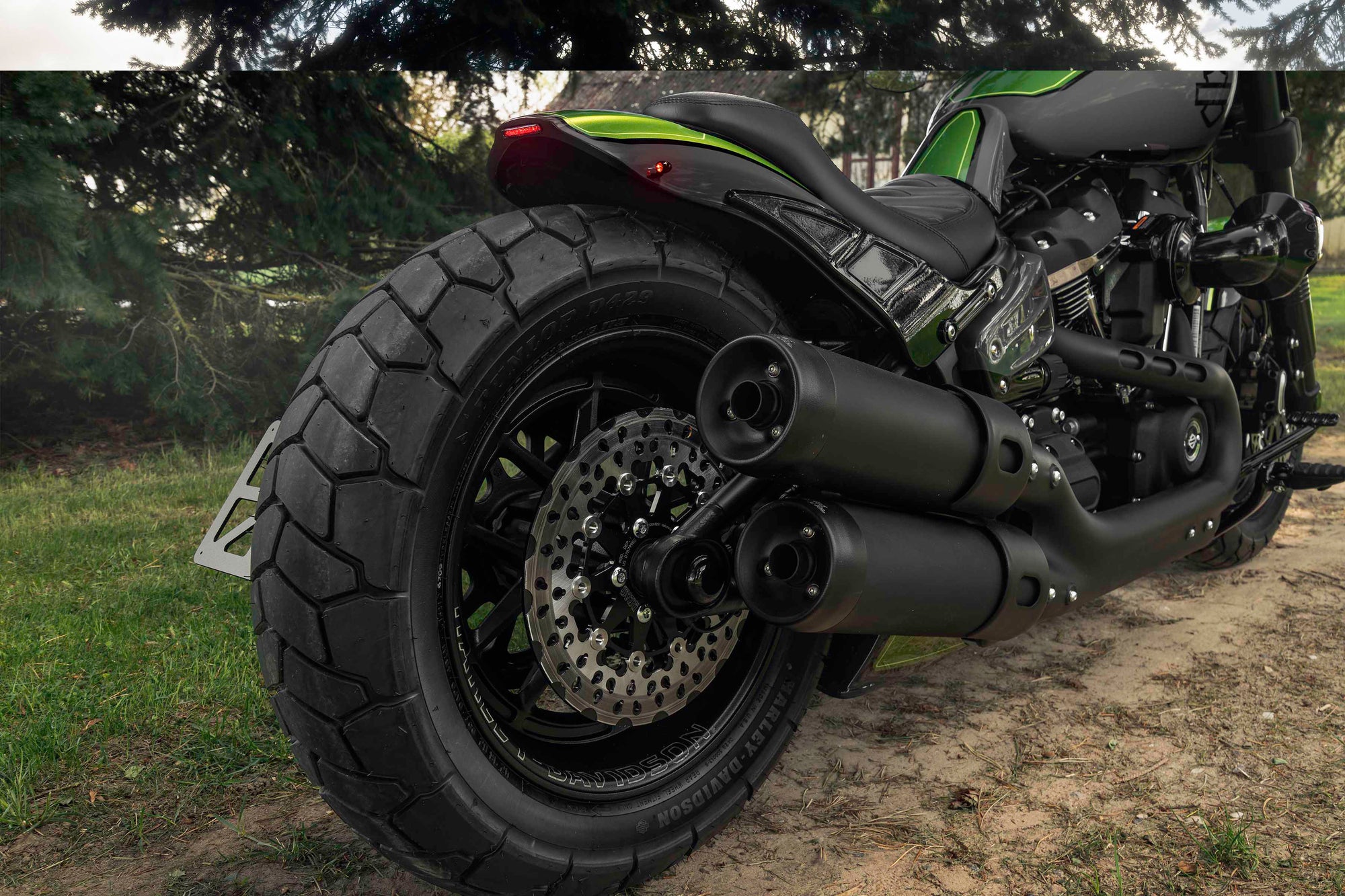 Zoomed Harley Davidson Fat Bob motorcycle with Killer Custom parts from the rear with some trees in the background