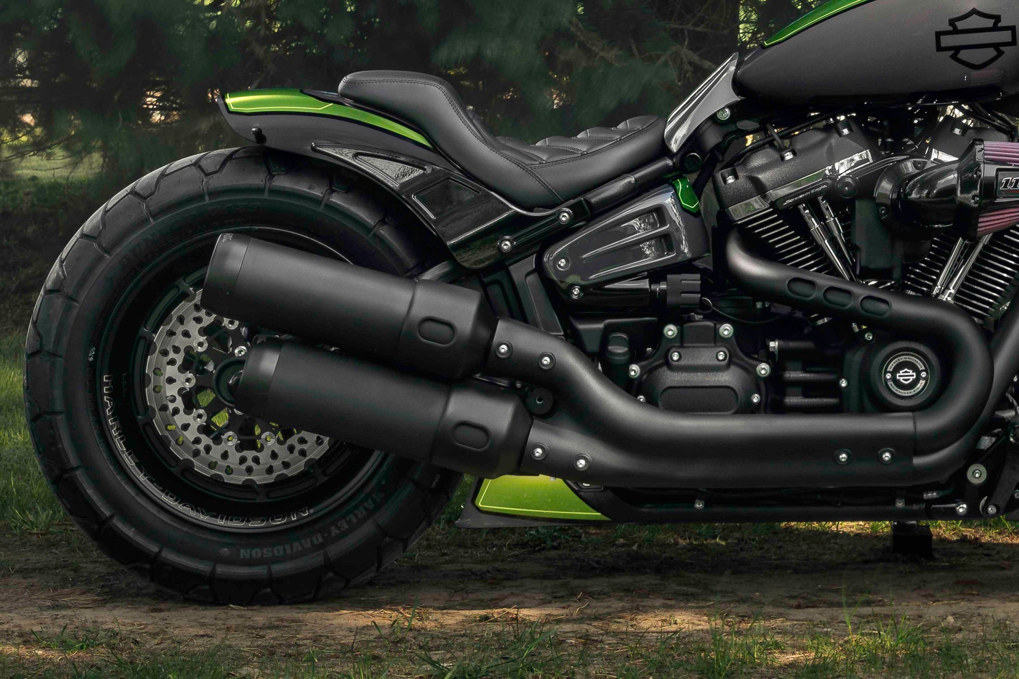 Zoomed Harley Davidson Fat Bob motorcycle with Killer Custom parts from the side with some trees in the background